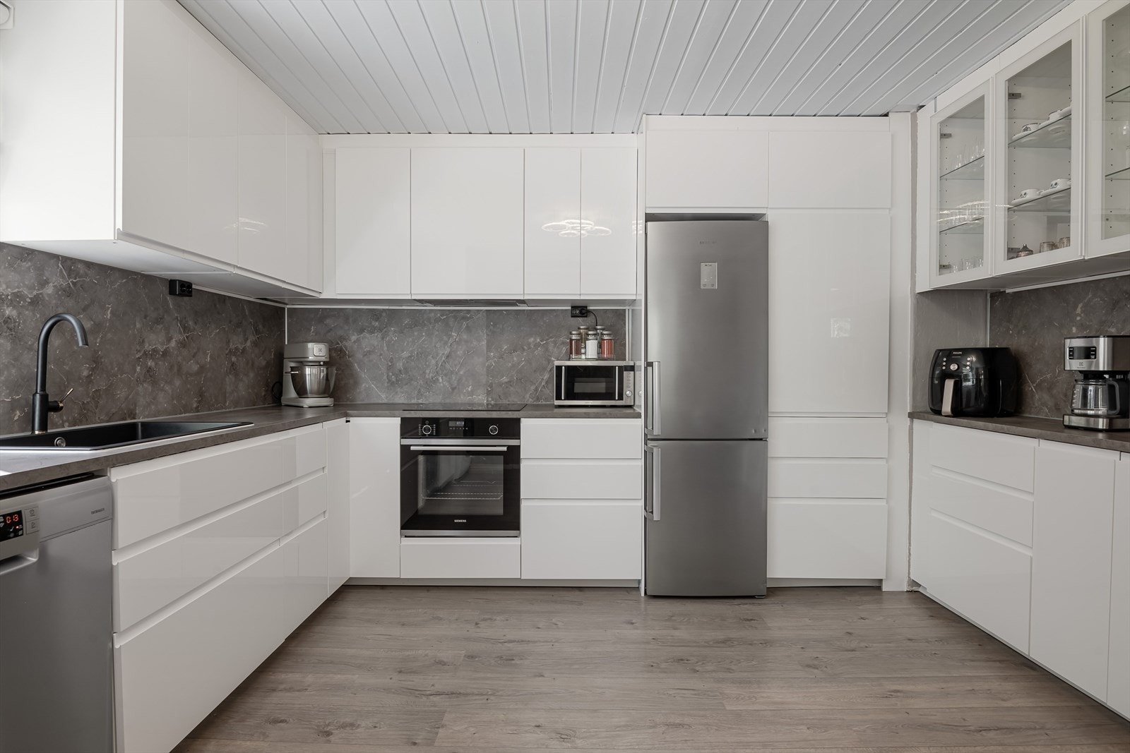 Du har god skap- og benkeplass i innredningen som har hvite glatte fronter og laminert benkeplate med nedfelt oppvaskkum. Både stilrent og praktisk med plater i benkeryggen og takhøye overskap. Galleribilde