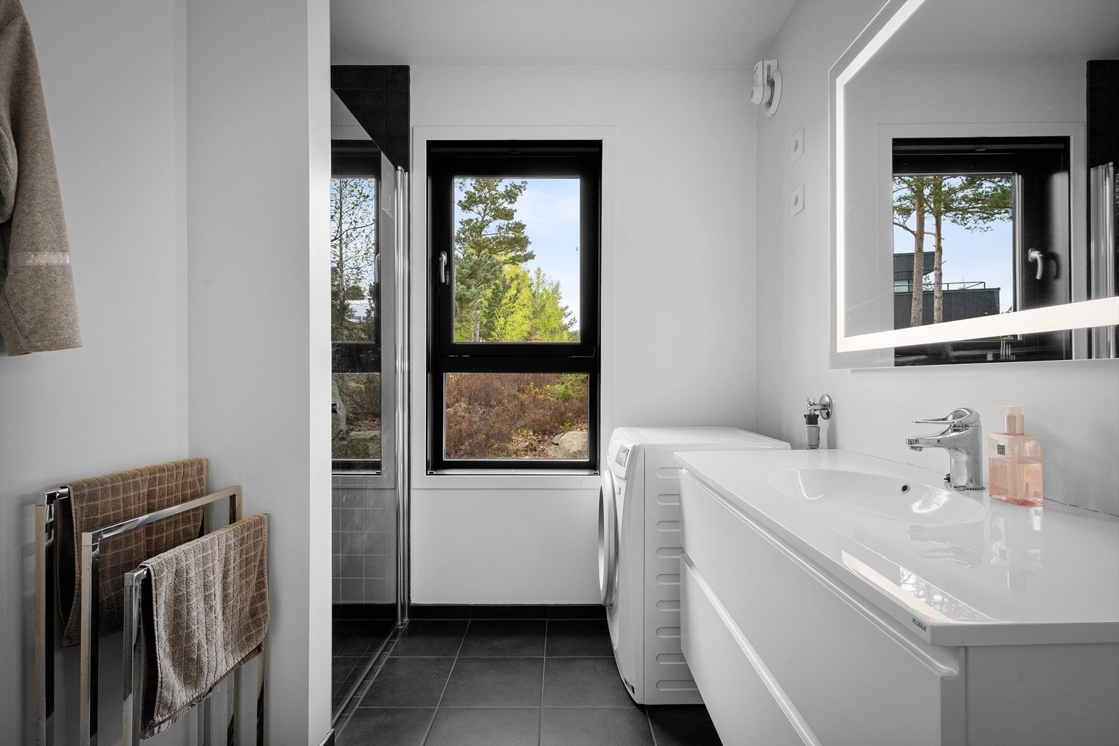 Hovedbadet med dusjhjørne. Flislagt på gulv. Lys i speil og vindu for naturlig lys. Kombinert vaskerom. Galleribilde