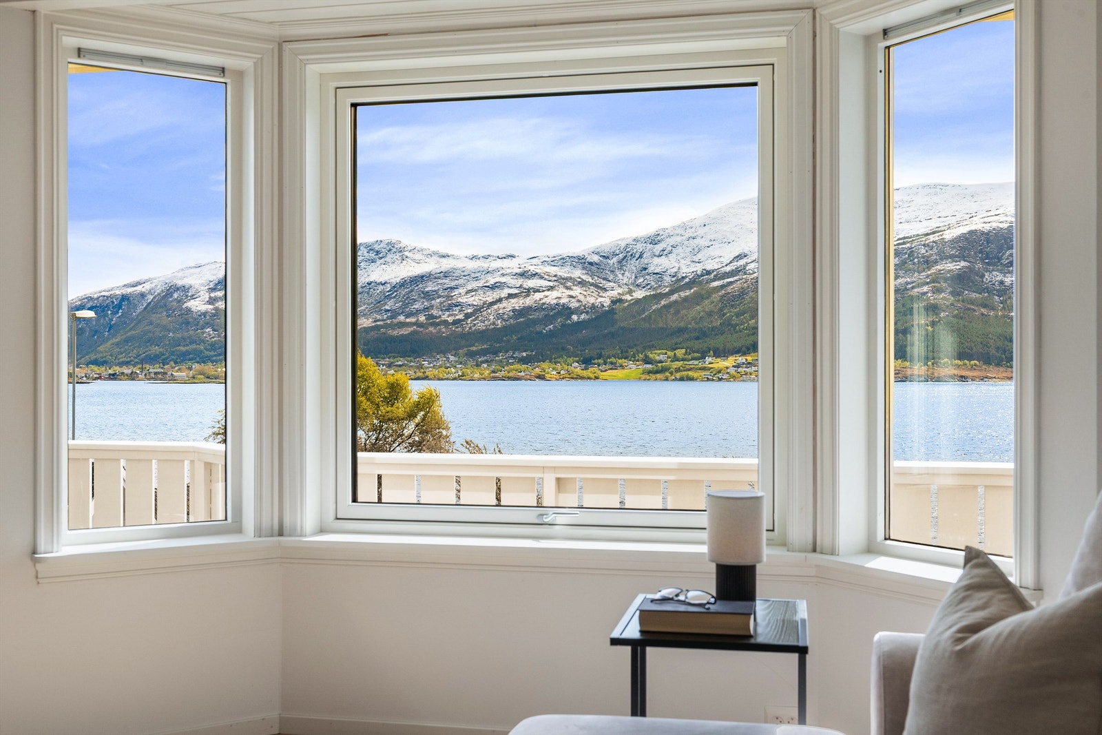 Store vindusflater i stuen rammer inn utsikten mot fjorden og fjellene Galleribilde