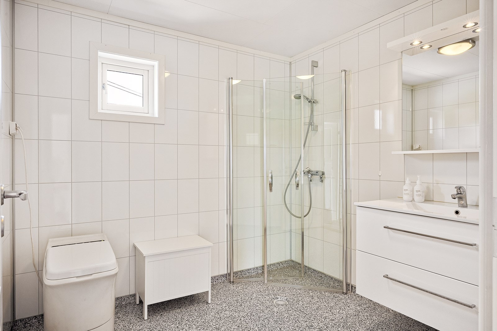 Badet er pent innredet med varme i gulvet, gulvbelegg og baderomspanel på veggene som gir et helhetlig og vedlikeholdsvennlig uttrykk. Galleribilde