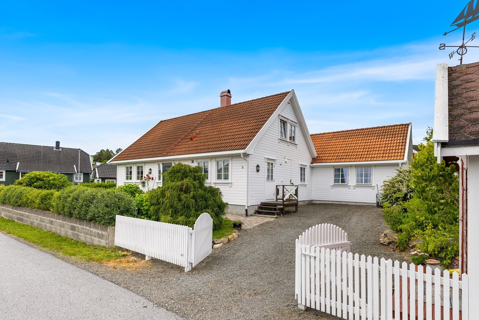 Klassisk fasade med hvitmalt kledning, sprossevinduer og et innbydende inngangsparti. Galleribilde