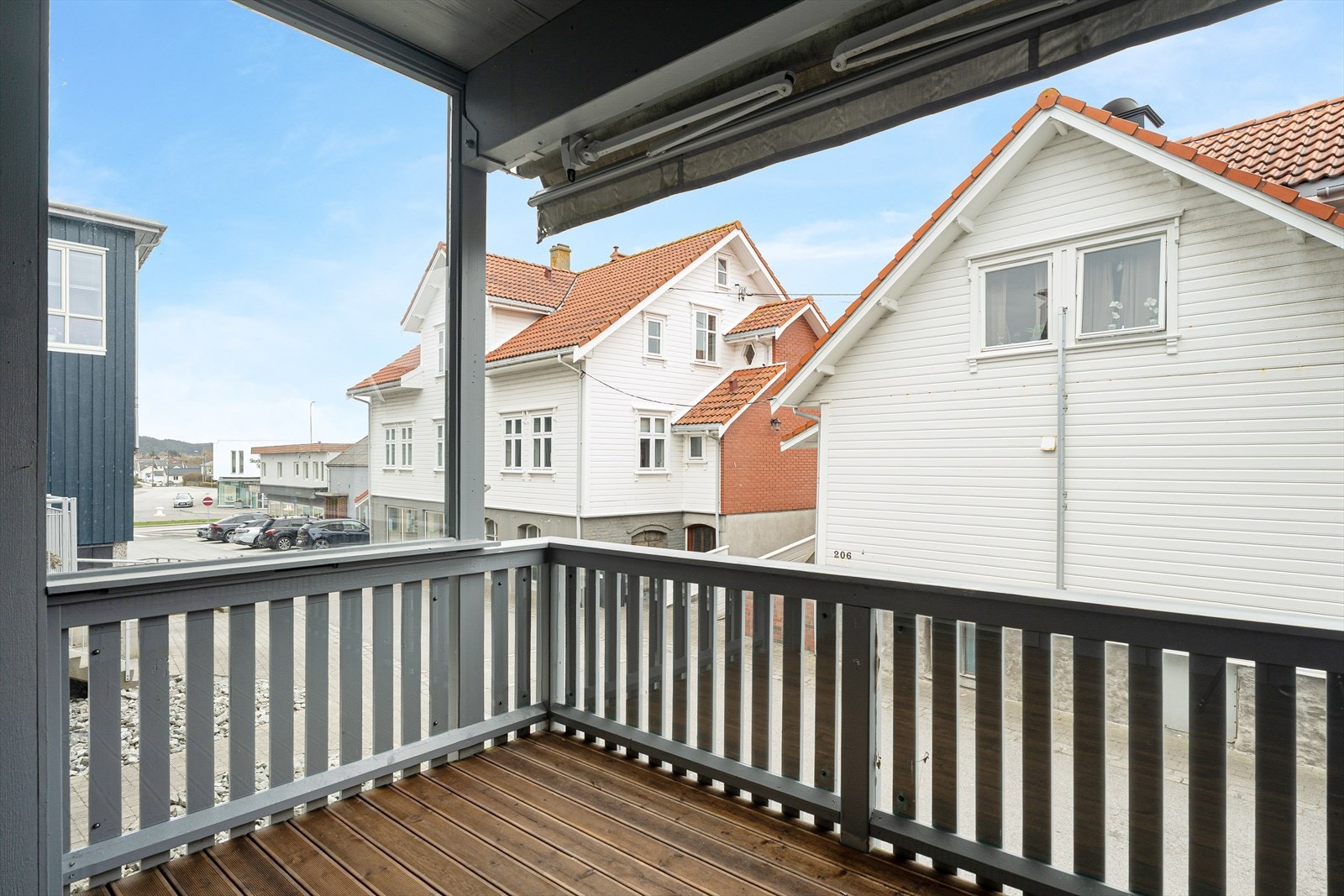 Balkongen har rekkverk og terrassebord av tre, samt innslag av plexiglass over rekkverket for vindskjerming Galleribilde