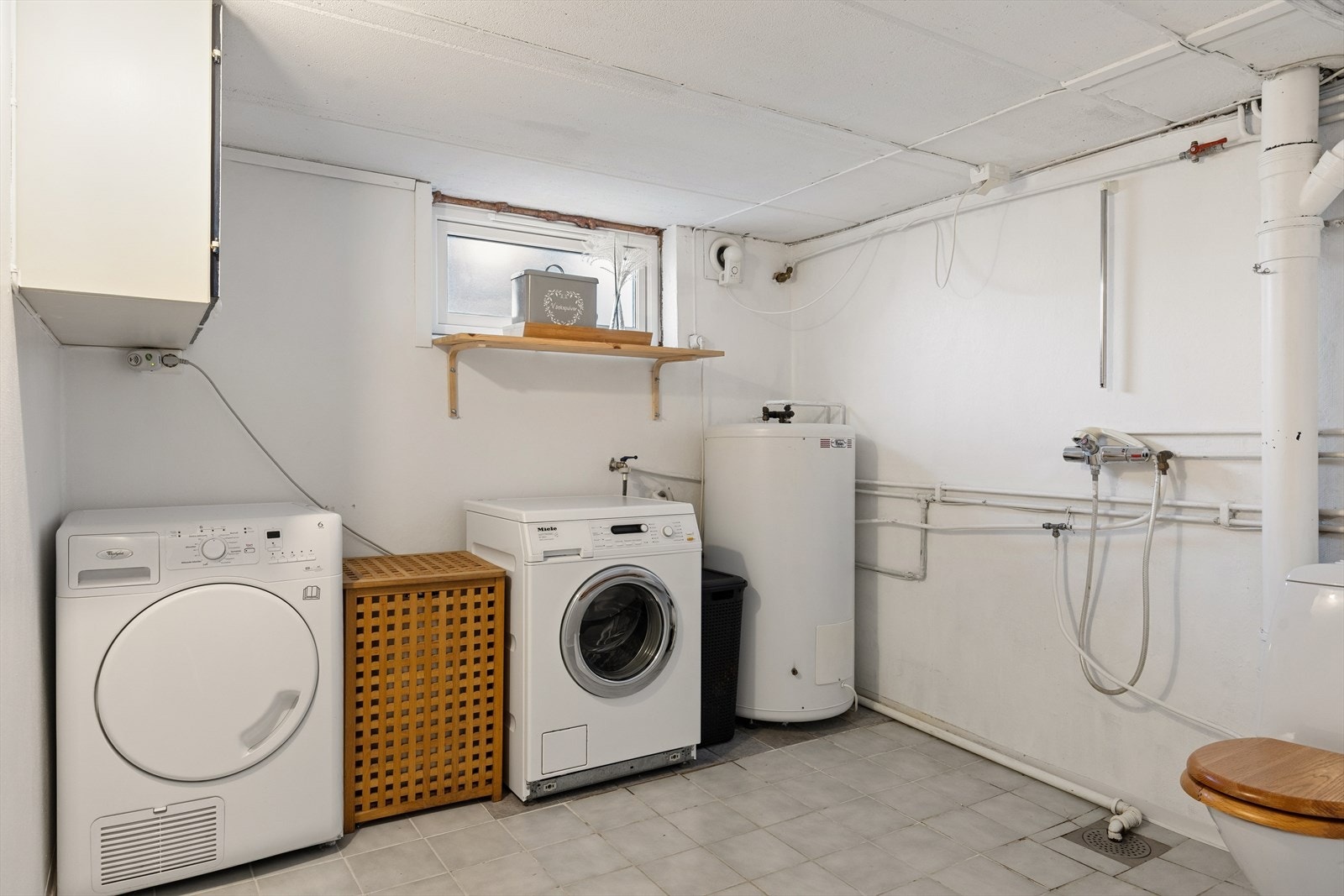 Romslig vaskerom med flislagt gulv, toalett og varmtvannstank på 200 liter fra 2002. Galleribilde
