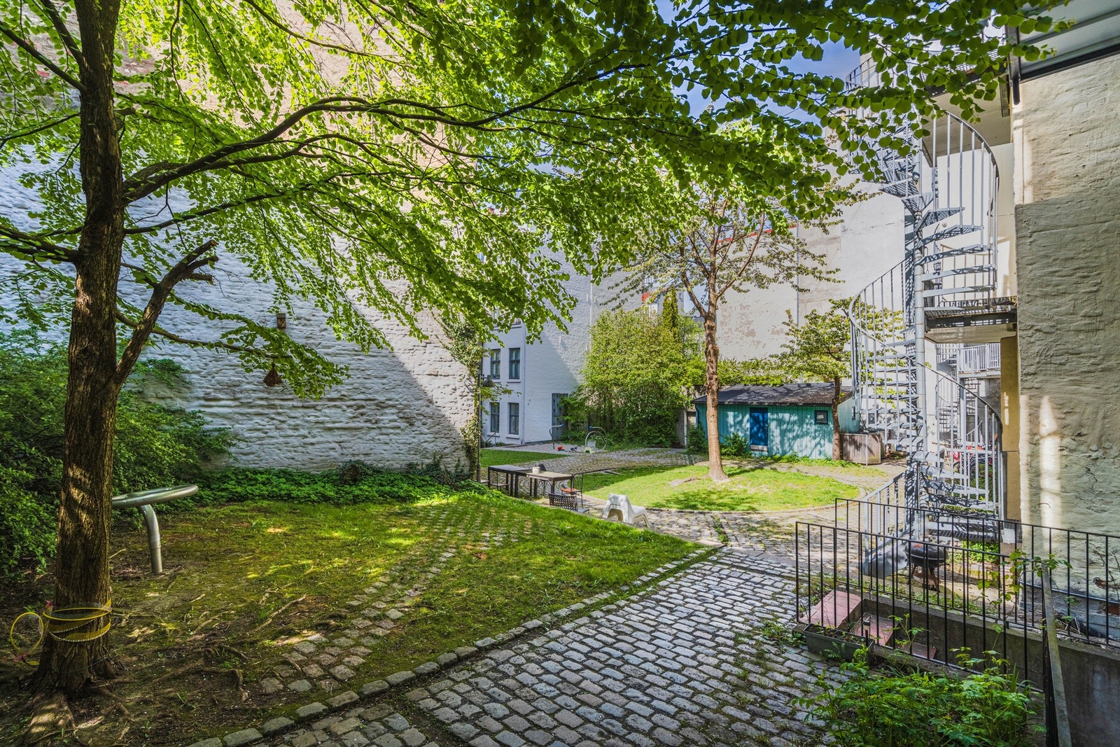 Hyggelig bakgård med brostein, grønne innslag og sykkelparkering - et skjermet uteområde midt i byen Galleribilde