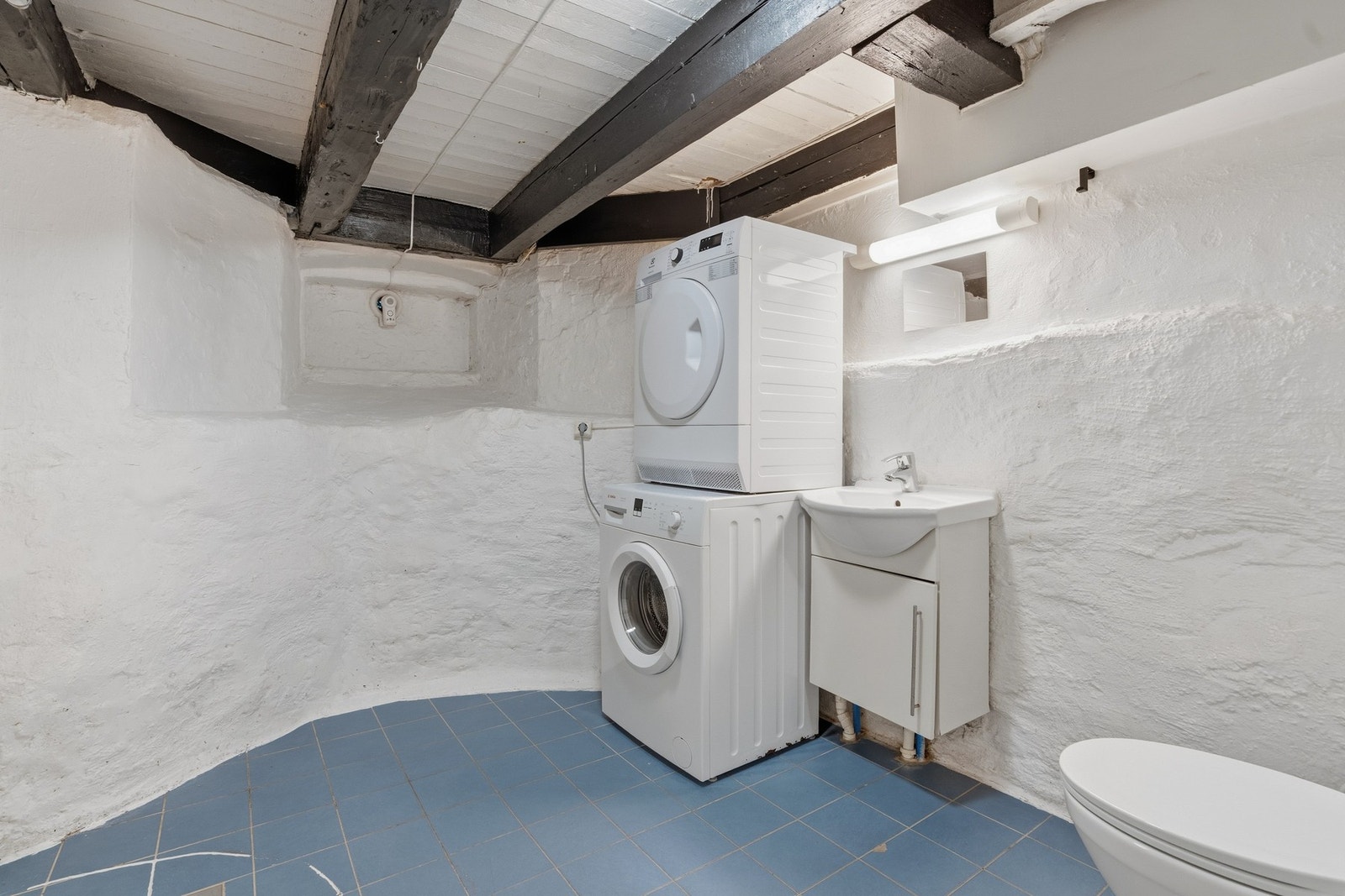Badet har malte betongvegger og flislagt gulv med elektriske varmekabler. Det er elektrisk avtrekksvifte. Galleribilde