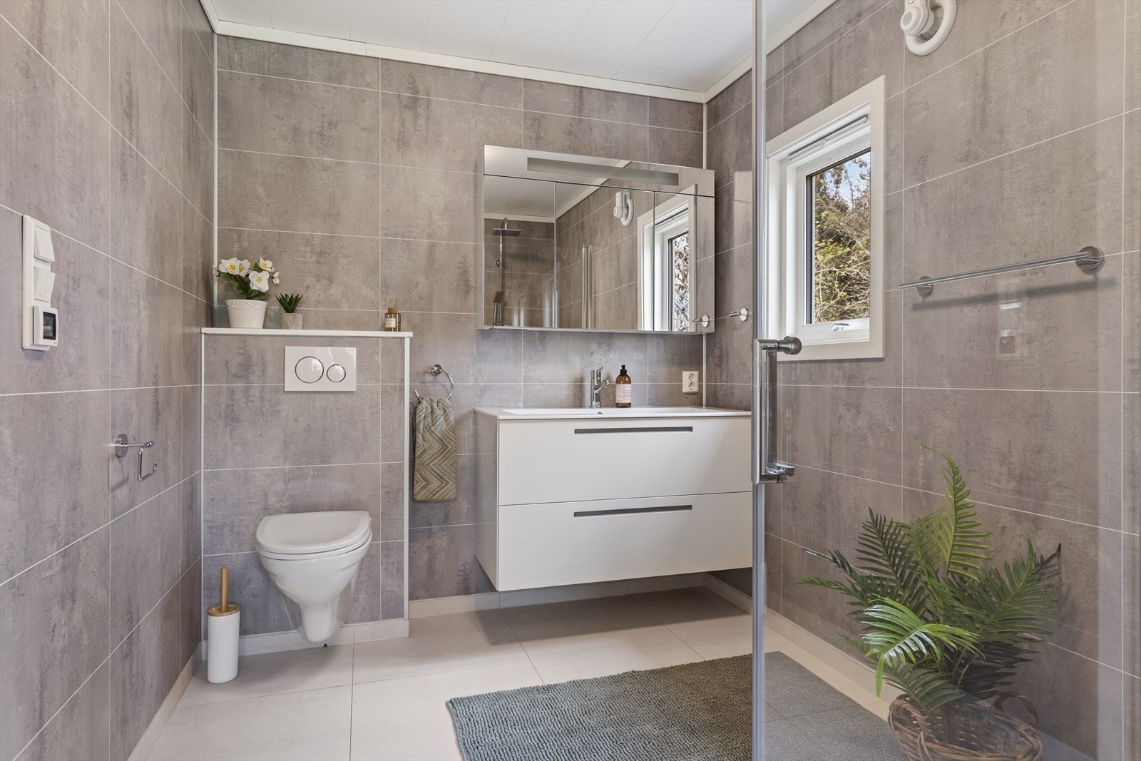 Badet er innredet med baderomsinnredning, vegghengt toalett og dusjnisje, og har elektrisk styrt avtrekksvifte. Galleribilde