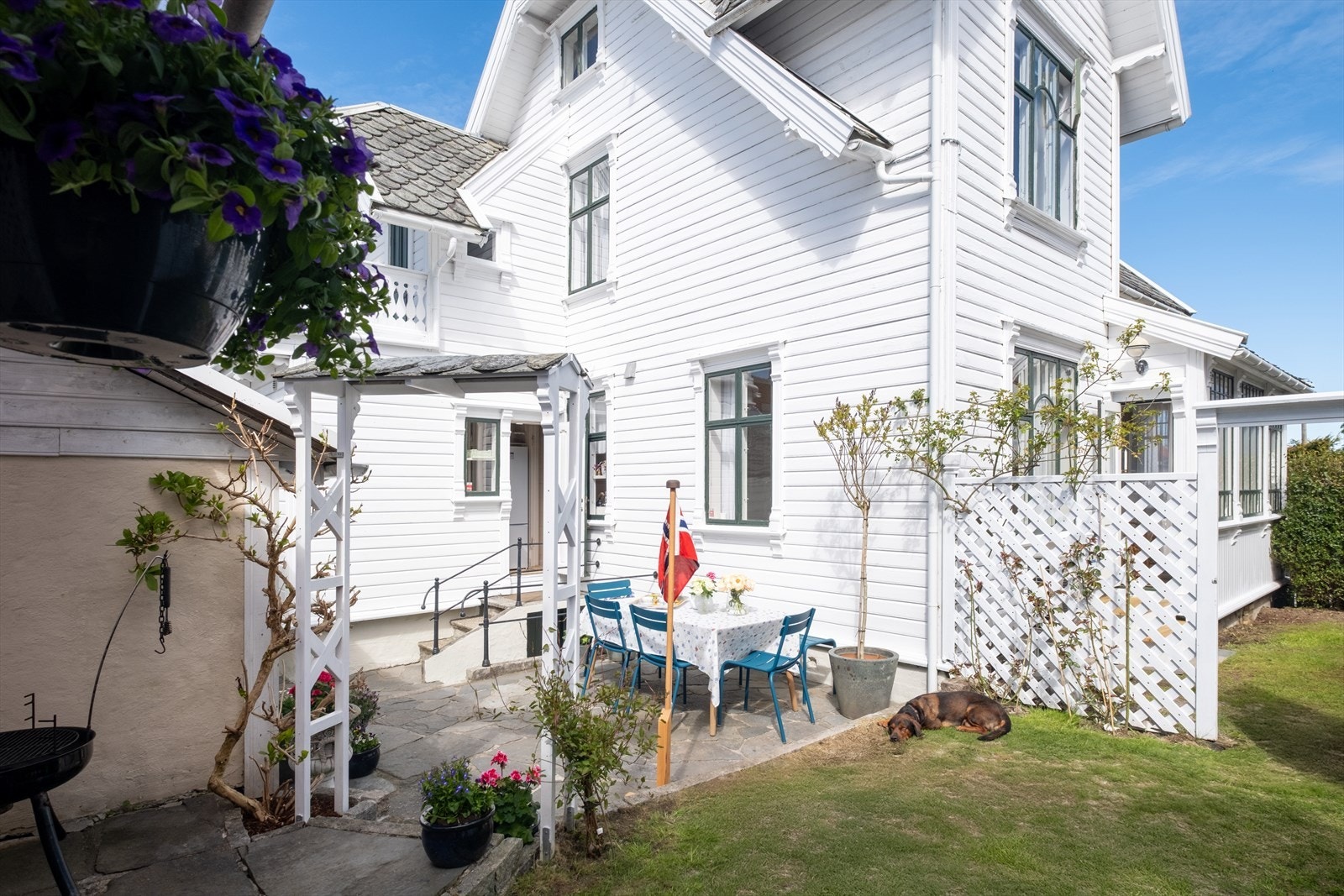 Sjarmerende hageområde med lune uteplasser, vakre detaljer og klassisk trehusbebyggelse som rammer inn eiendommen. Galleribilde