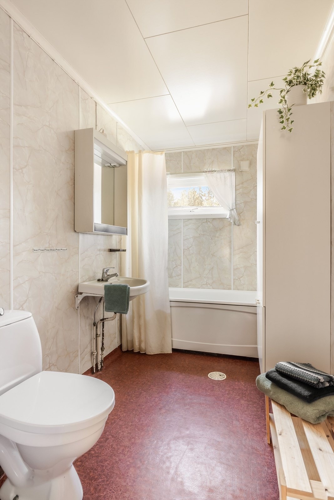 Baderommet er utstyrt med vegghengt servant med speilskap over, badekar med forheng og gulvstående toalett. Galleribilde