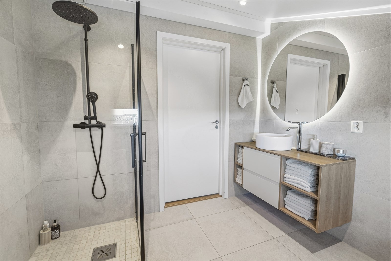 Badet er utstyrt med vegghengt toalett, dusjhjørne med glassvegger, veggskap, samt baderomsinnredning med bolleservant og speil. Galleribilde