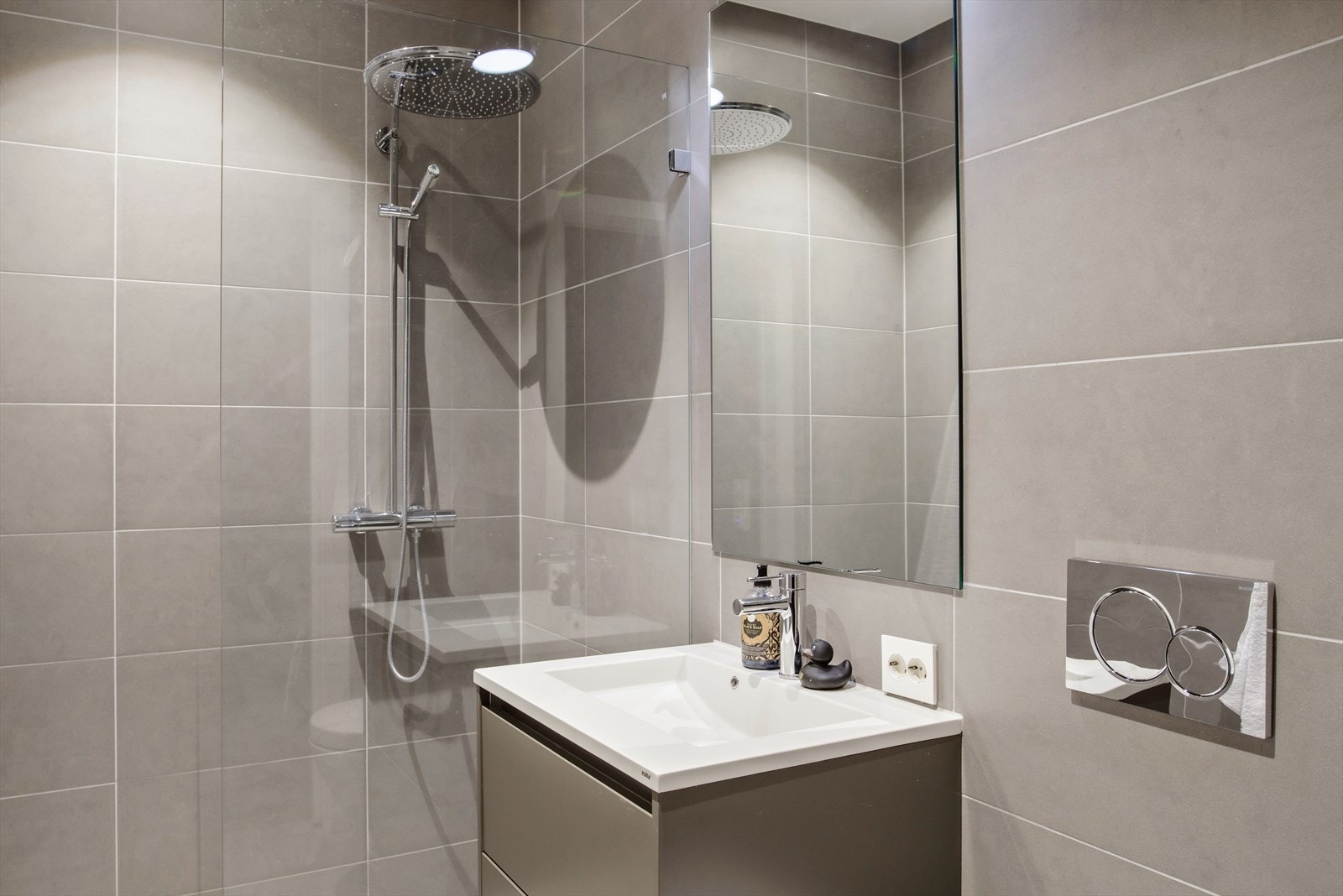 Badet er av god størrelse med pent flisvalg på både gulv og vegger, stor dusjnisje, servant, speil og vegghengt wc. Galleribilde