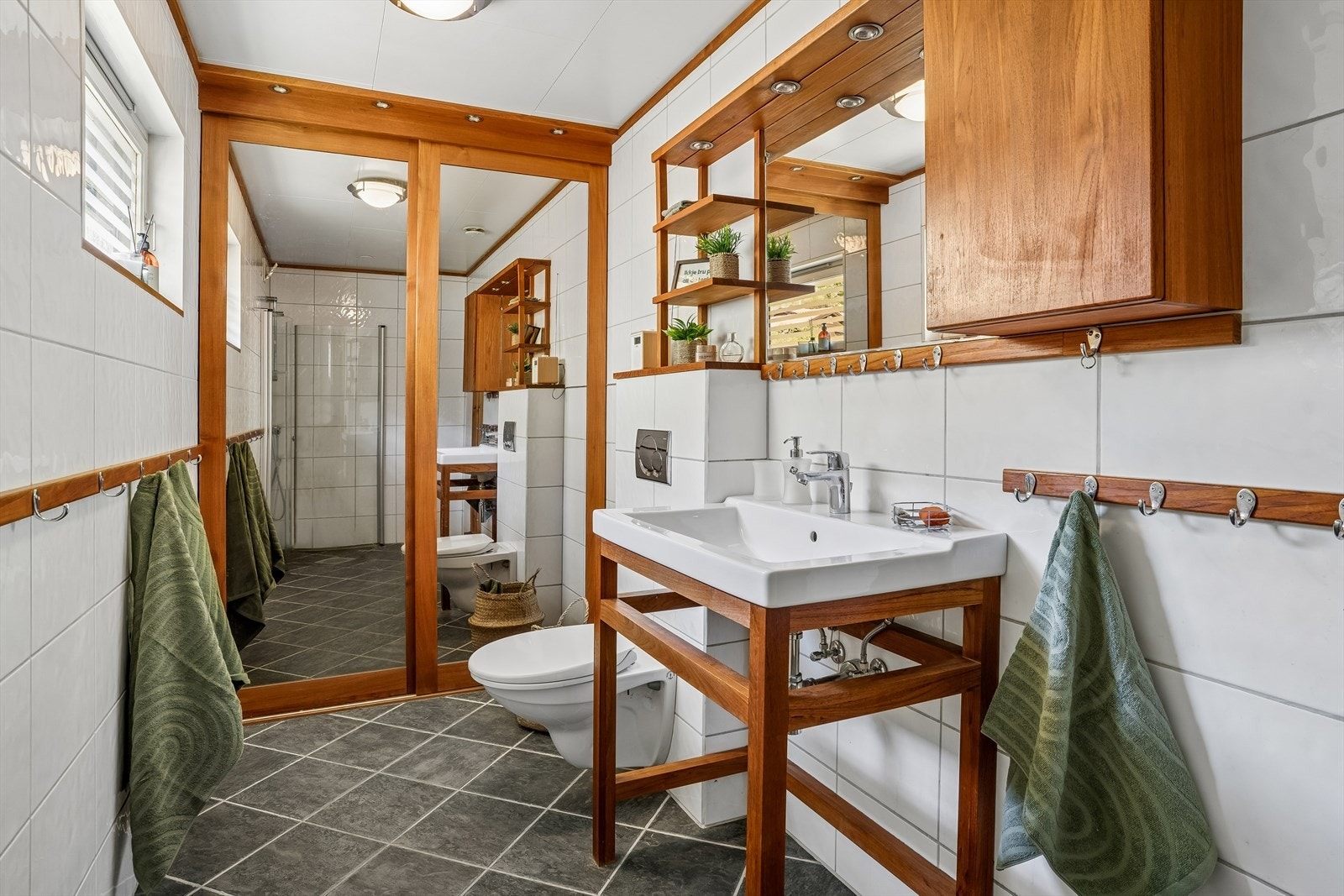 Badet er utstyrt med veggmontert klosett og har ein praktisk skyvedørsgarderobe for god oppbevaring. Galleribilde