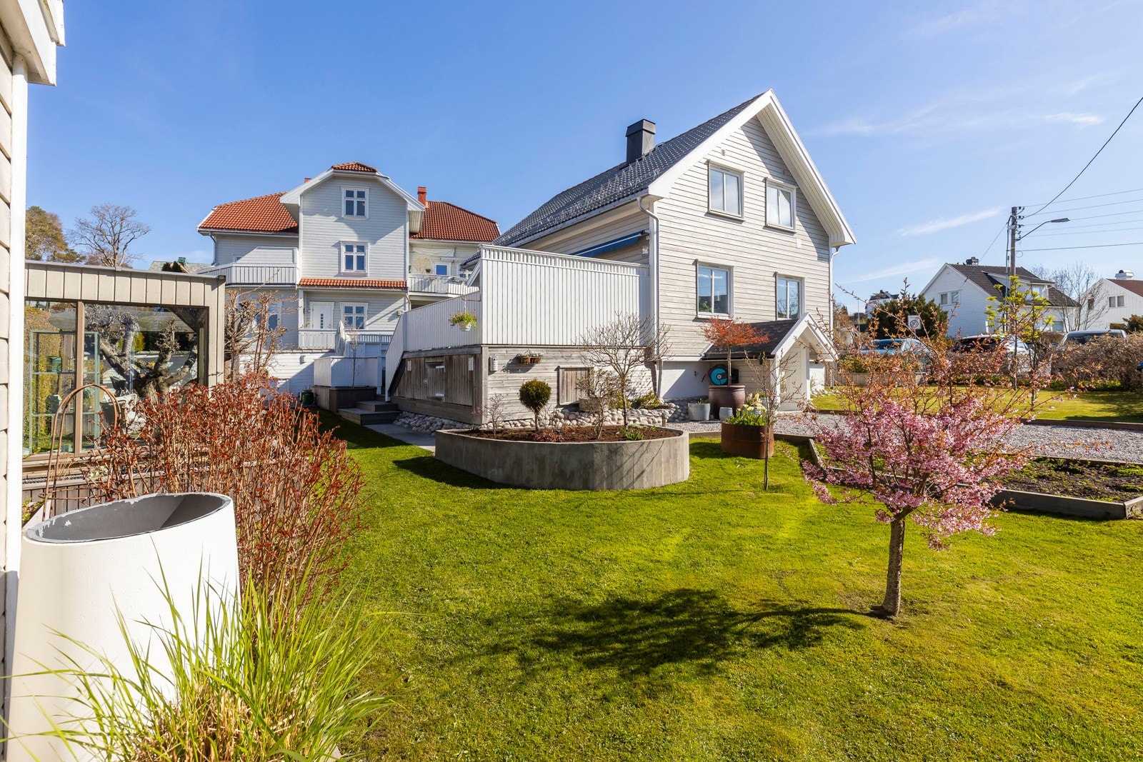 Eiendommen har en pent opparbeidet tomt med gress og beplantning, beplantet med vakre trær og busker som bidrar til et frodig og harmonisk uttrykk, og flotte uteområder som fungerer som en naturlig forlengelse av hjemmet. Galleribilde