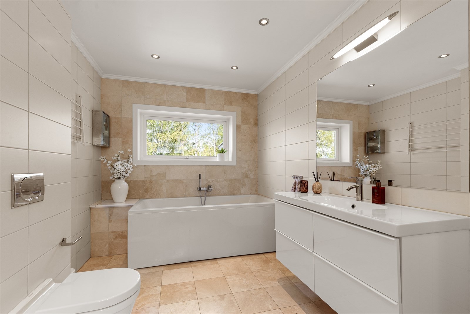 Badet i hovedetasjen er smakfullt innredet med fine fliser, moderne innredning vegghent toalett, dusj og badekar. Legg merke til sluse ned til vaskerom! Galleribilde