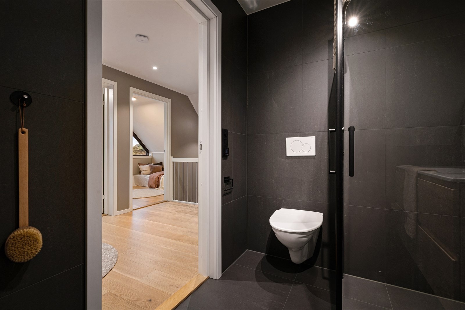Badet er praktisk innredet med en håndvask med underskap, speil med integrert belysning, vegghengt WC med drenshull og vendbare dusjdører som gir fleksibilitet i bruk. Galleribilde