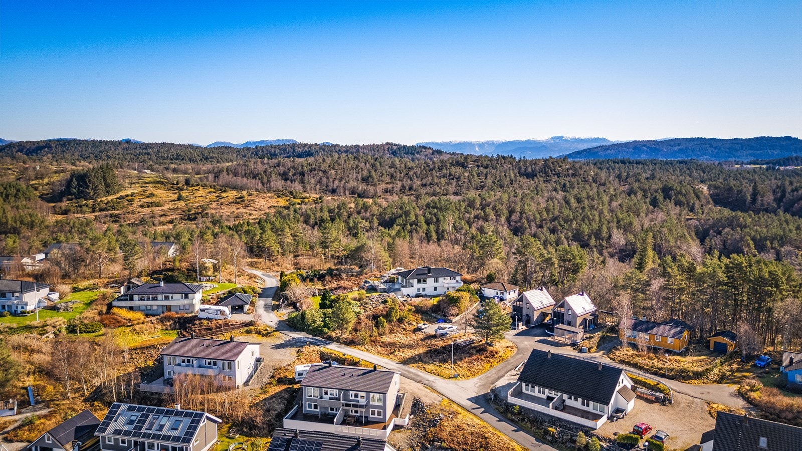 Sjarmerende boligområde omgitt av vakker natur og frodige skoger, med rolig atmosfære og flott utsikt mot fjellene i horisonten. Galleribilde