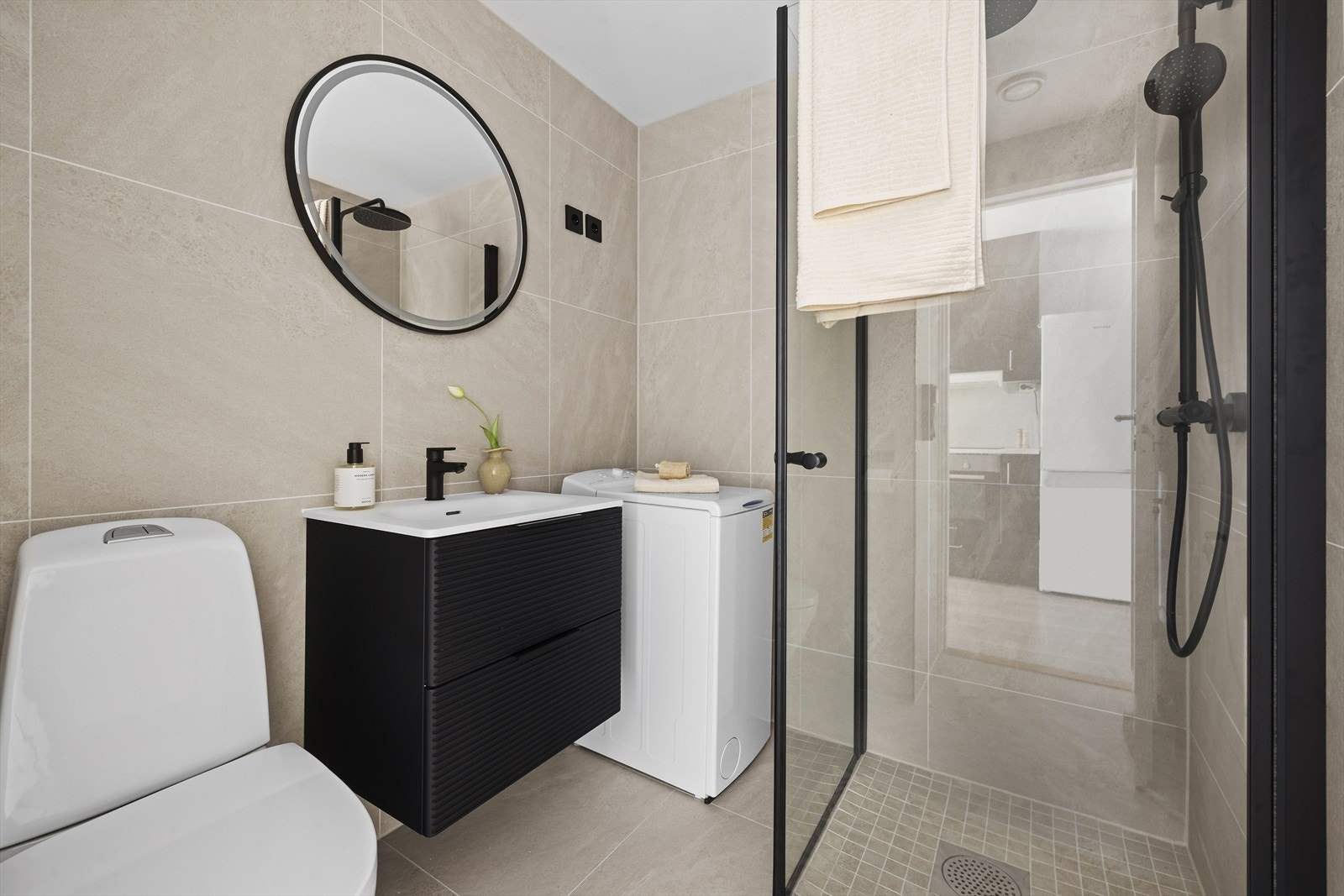 Badet ble oppgradert i 2026, med store fliser på gulv og vegger i en rolig, lys nyanse. Badet er utstyrt med toalett, servantinnredning og dusj Galleribilde