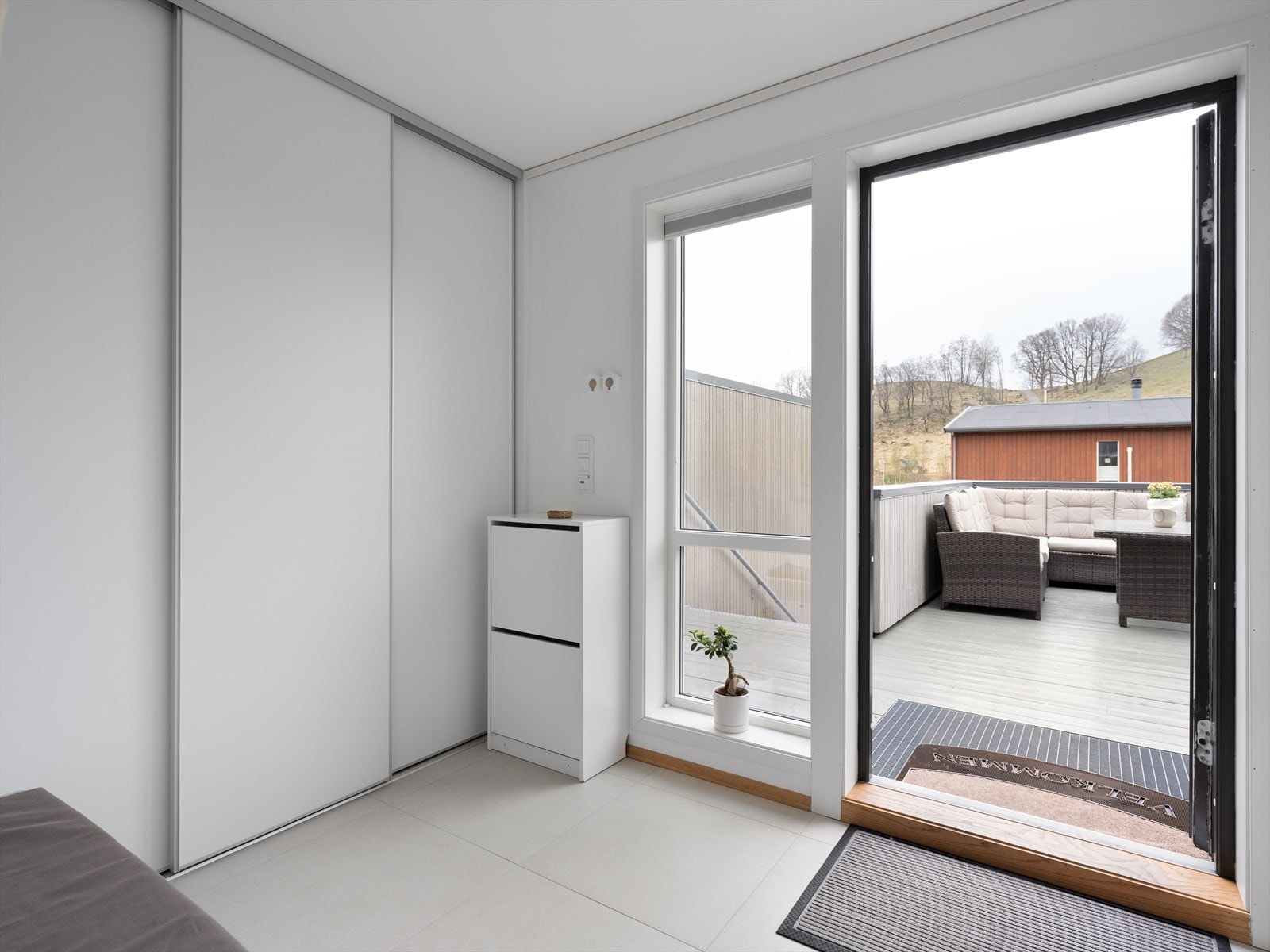 Velkommen inn! Romslig gang med skyvedørsgarderobe og fliser på gulvet Galleribilde