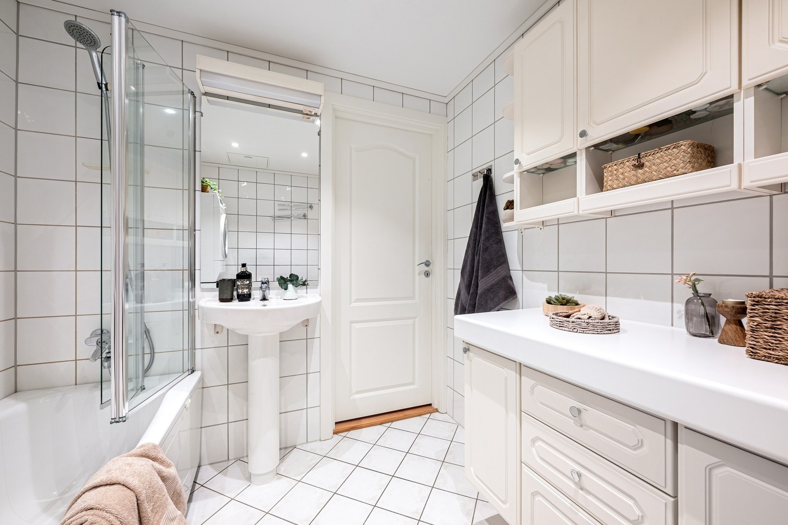 Badet har en praktisk utforming med servantskap, badekar med foldevegg i glass og mekanisk avtrekk. En funksjonell løsning for en større familieleilighet. Galleribilde