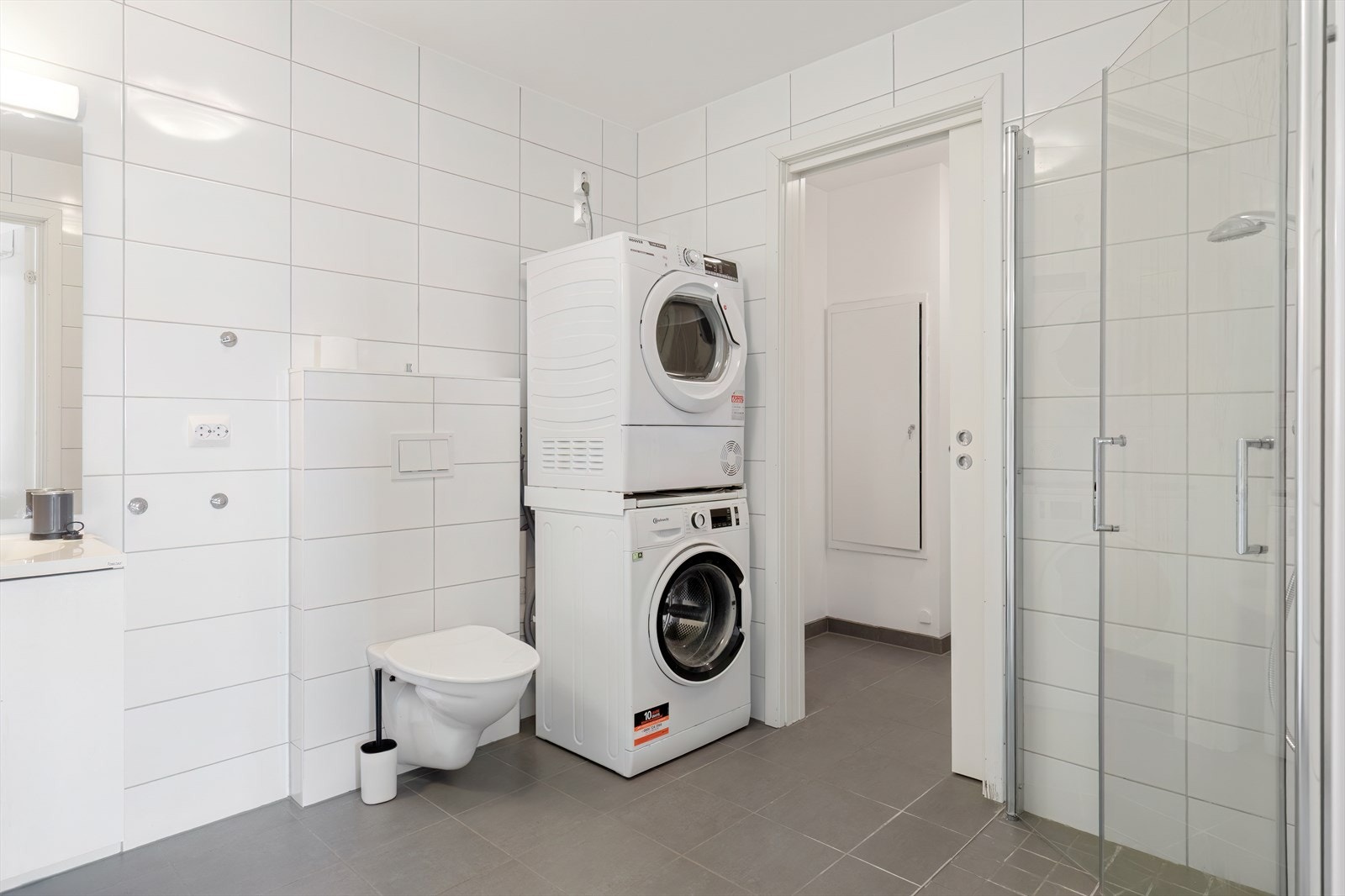 Badet er utstyrt med dusjsone, vegghengt toalett og opplegg for vaskemaskin. Galleribilde