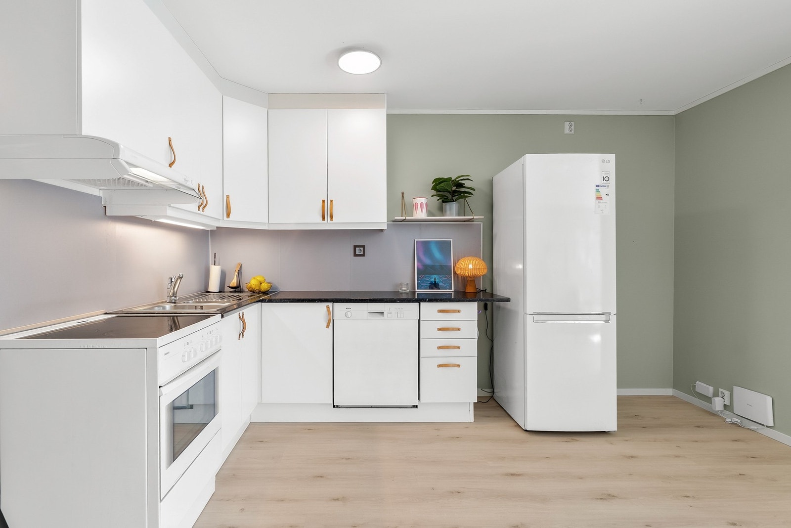 Kjøkkeninnredning med hvite, slette fronter og laminat benkeplate. Kitchenboard på vegg over benk. Galleribilde