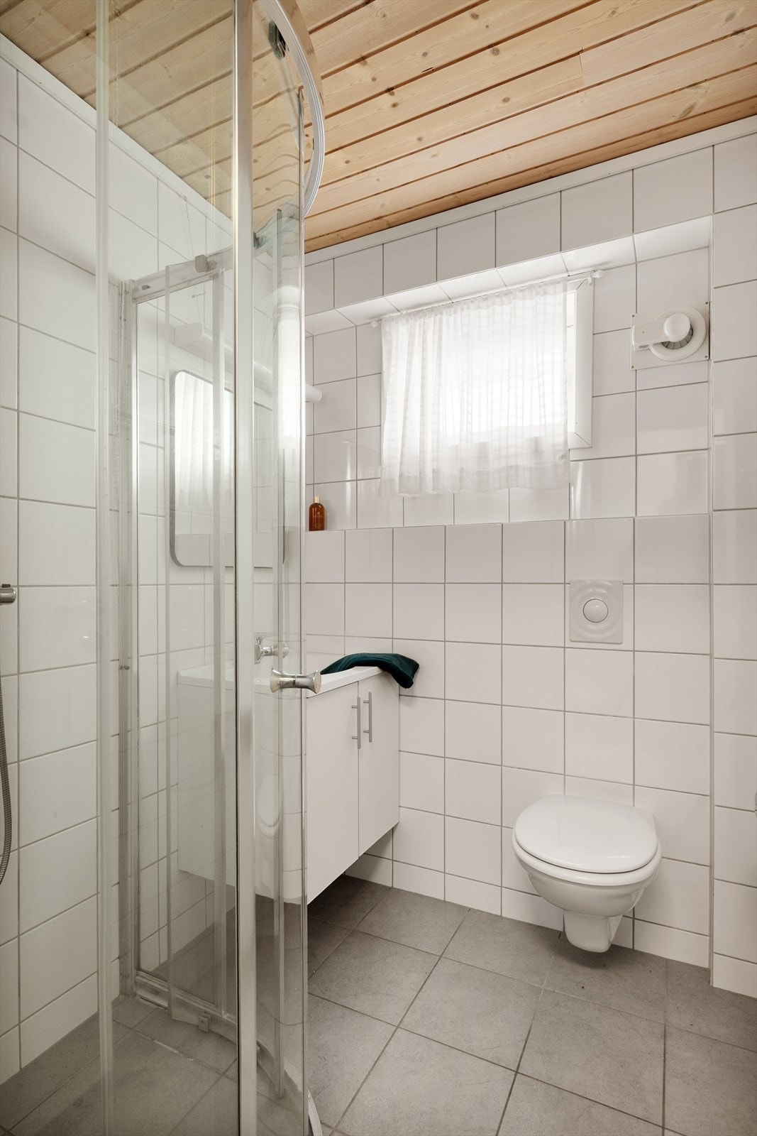 Helfliset bad med varme i gulv. Badet er utstyrt med servant, vegghengt toalett og dusjhjørne. Galleribilde