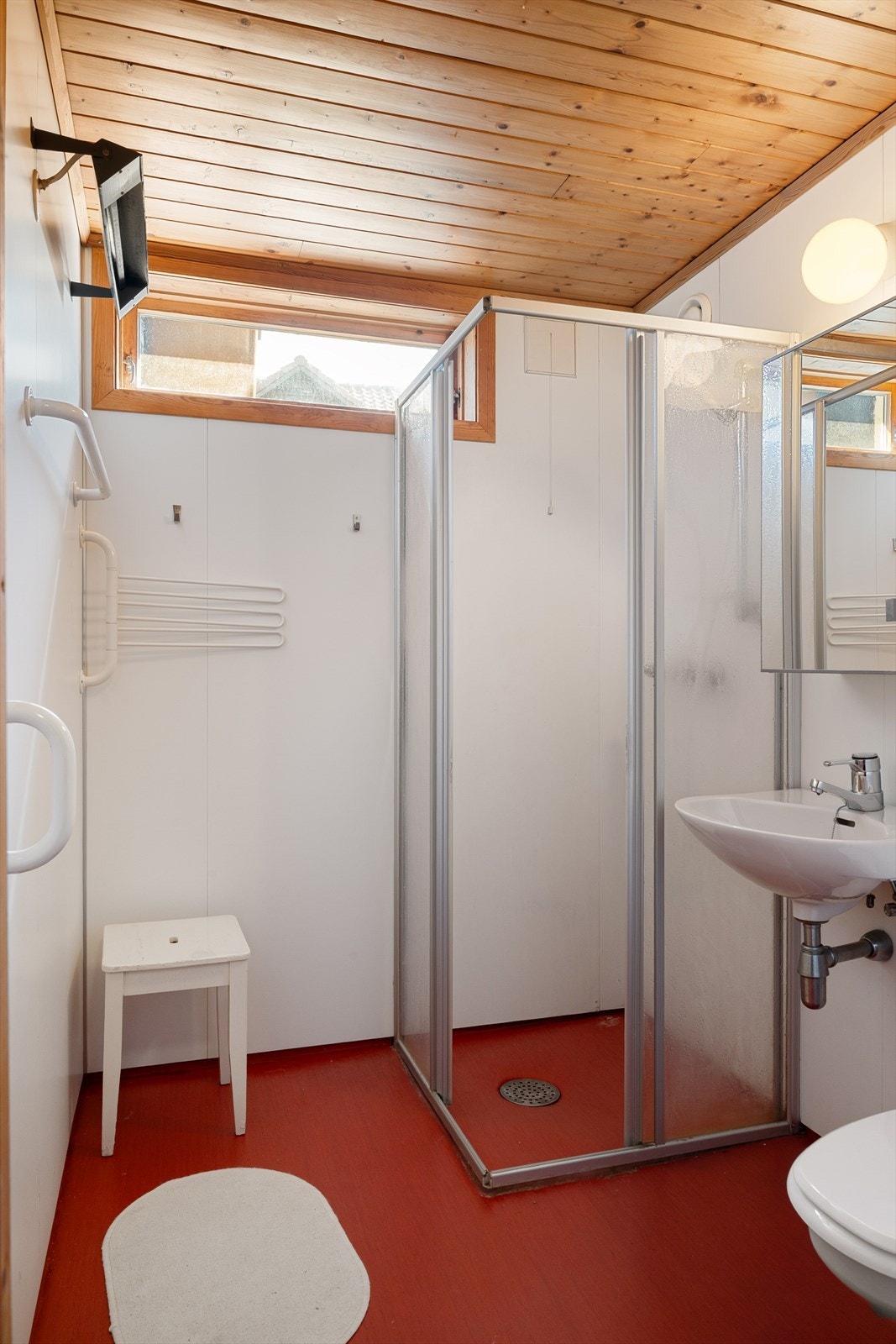 Badet med vinylbelegg på gulv og baderomsplater på vegger. Innredet med toalett, enkel servant og dusjhjørne. Galleribilde