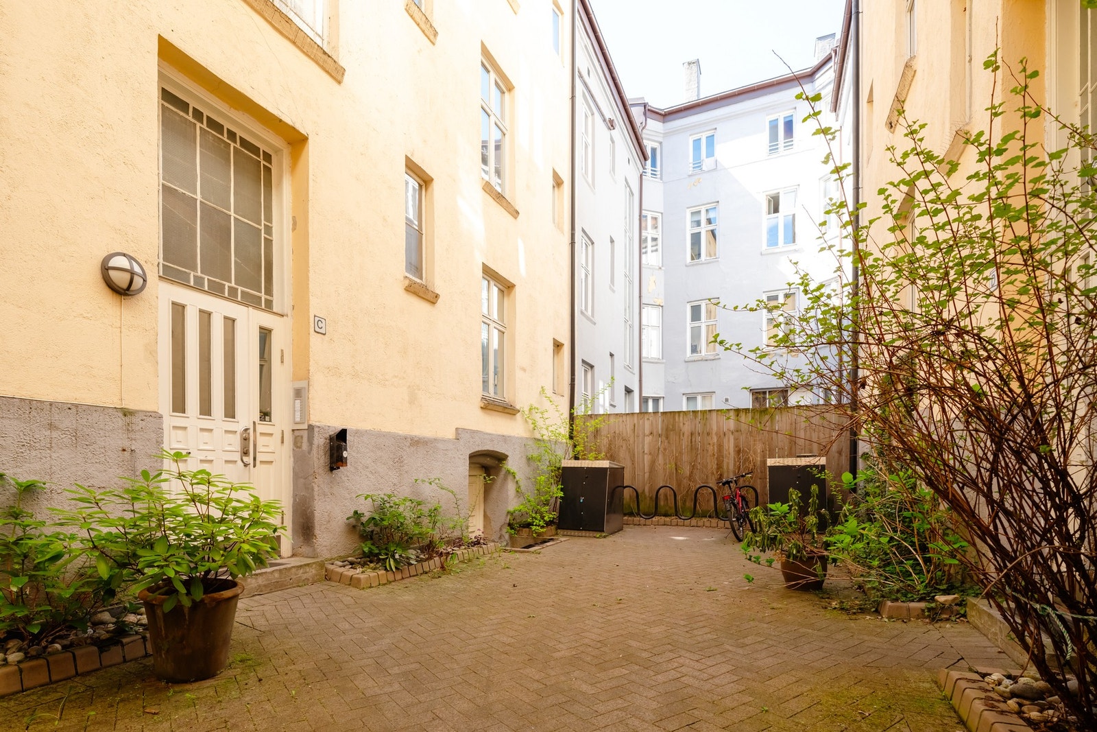 Bakgården er steinlagt med oppbevaring for sykkel og barnevogn Galleribilde