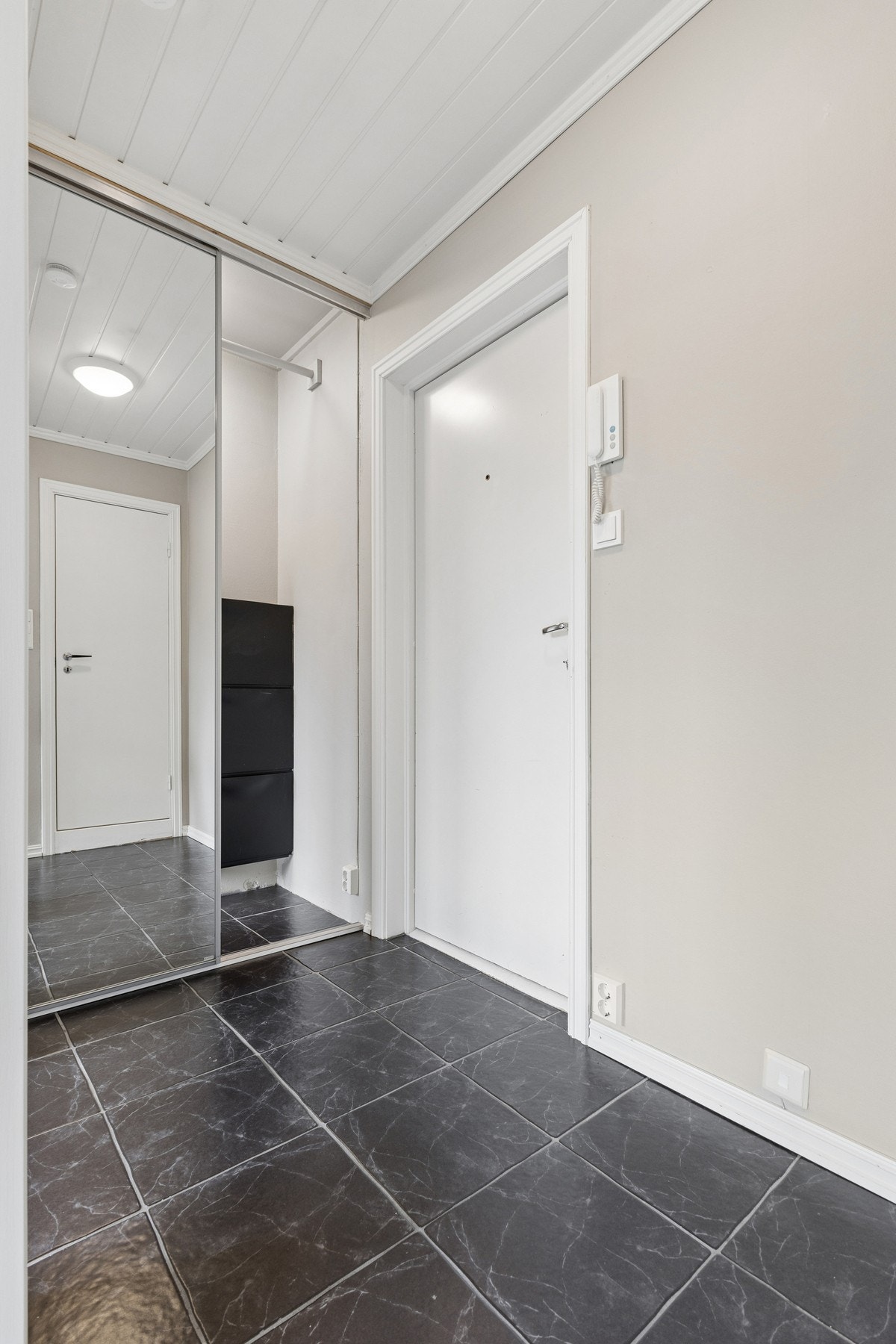 Entréen har flislagt gulv og en romslig skyvedørsgarderobe med speilfronter. Galleribilde