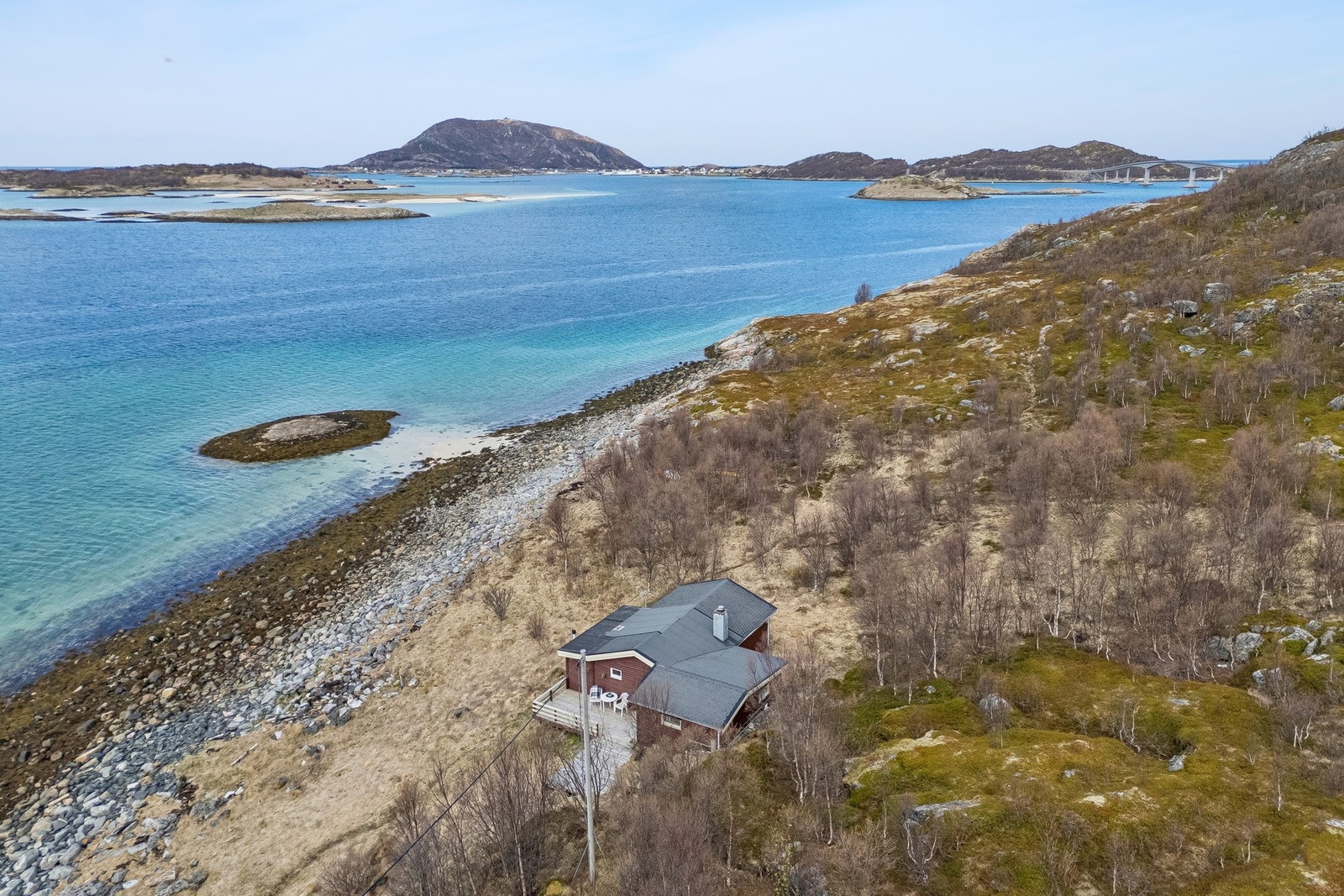 Fritidsbolig med tilhørende naust, beliggende på en naturtomt i et skrående terreng helt ned til sjøen. Galleribilde