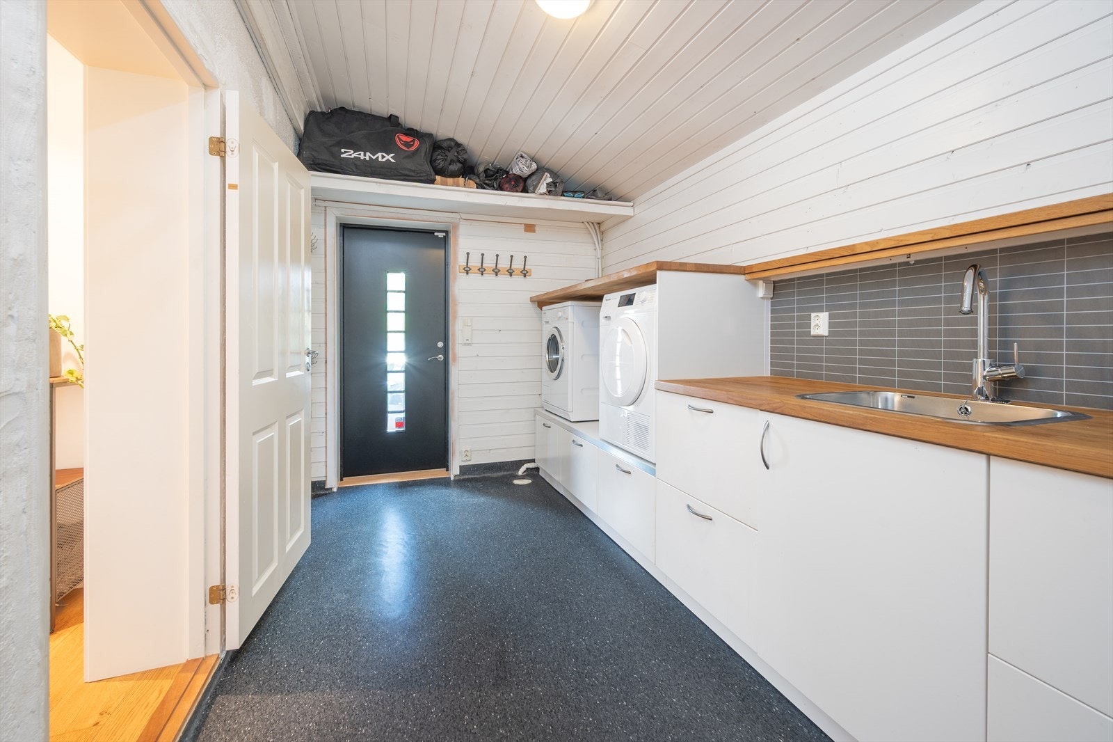 Separat vaskerom med innredning, utslagsvask og opplegg for vaskemaskin. Rommet har vinylbelegg med varmekabler. Galleribilde