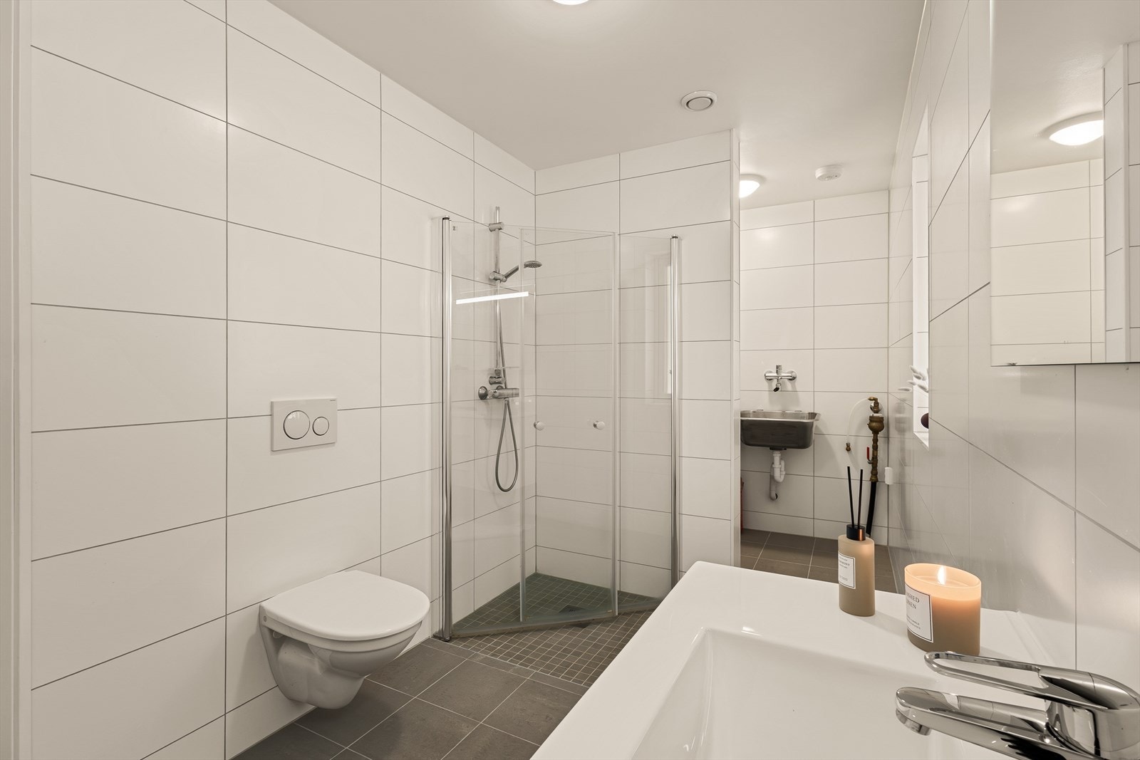 Badet er utstyrt med servant med møblement/speil, belysning, vegghengt toalett, dusjgarnityr, dusjhjørne og opplegg for vaskemaskin. Galleribilde