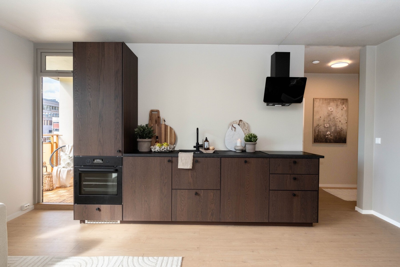 Tidsriktig og moderne kjøkken i mørk eikefarge og svart laminert benkeplate. Galleribilde