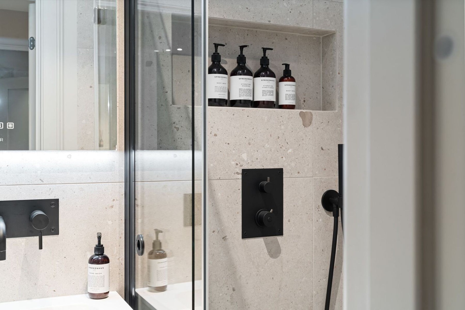 Badet er utstyrt med dusjnisje med glassvegger, vegghengt toalett, innbygd armatur, servant med innredning og speil, samt varmekabler i gulv. Galleribilde