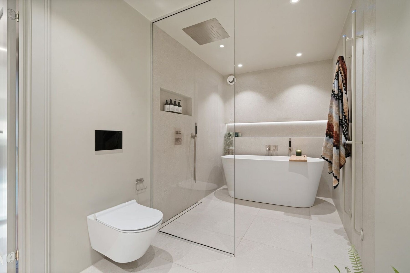 Badet er innredet med badekar, dusjnisje med glassdør, dobbel servant med tilhørende innredning, vegghengt toalett og elektriske håndkletørkere. Galleribilde
