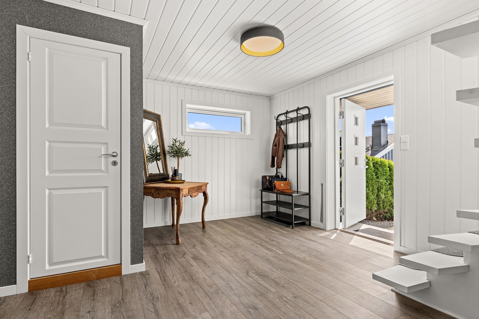 Romslig entré med god plass til garderobeløsninger. Den malte tretrappen binder etasjene sammen. Galleribilde