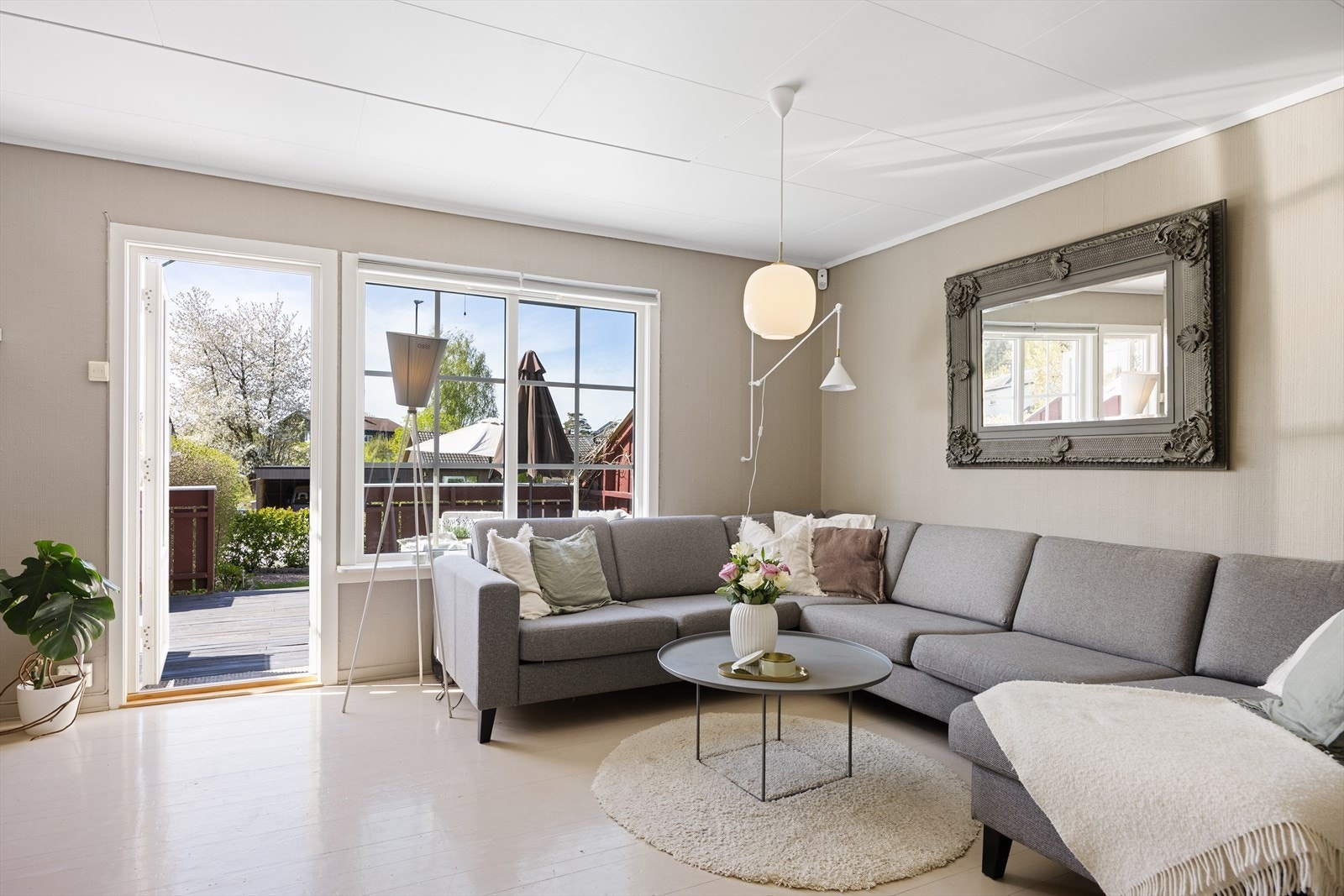 Pen og romslig stue med overflater i tidsriktige fargetoner og store vindusflater som slipper inn godt med naturlig lys. Galleribilde