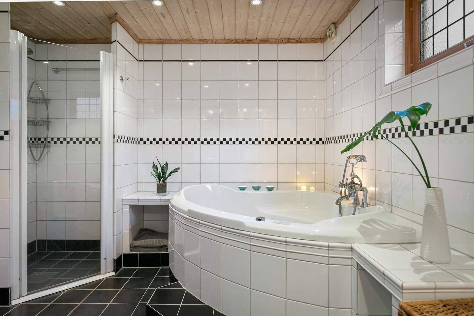 I det ene hjørnet av rommet er det et innfliset boblebad og i et annet hjørne en dusjnisje med glassdør. Galleribilde