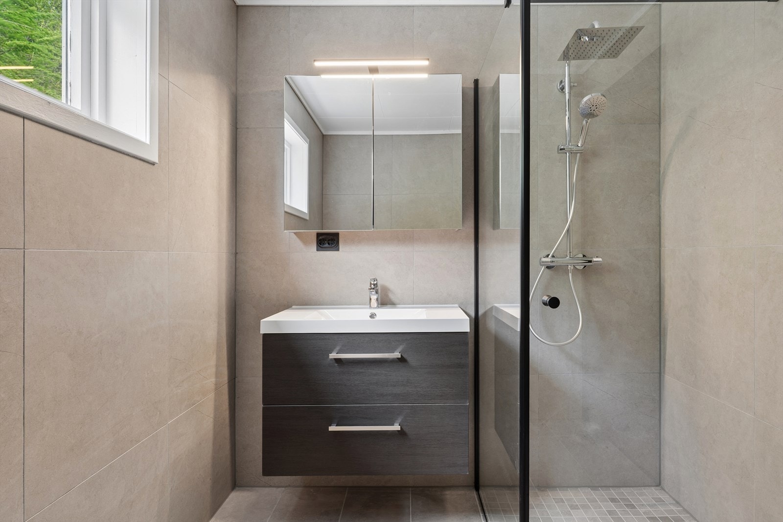Badet er utstyrt med dusjhjørne med regndusj og hånddusj, toalett og en moderne baderomsinnredning. Galleribilde