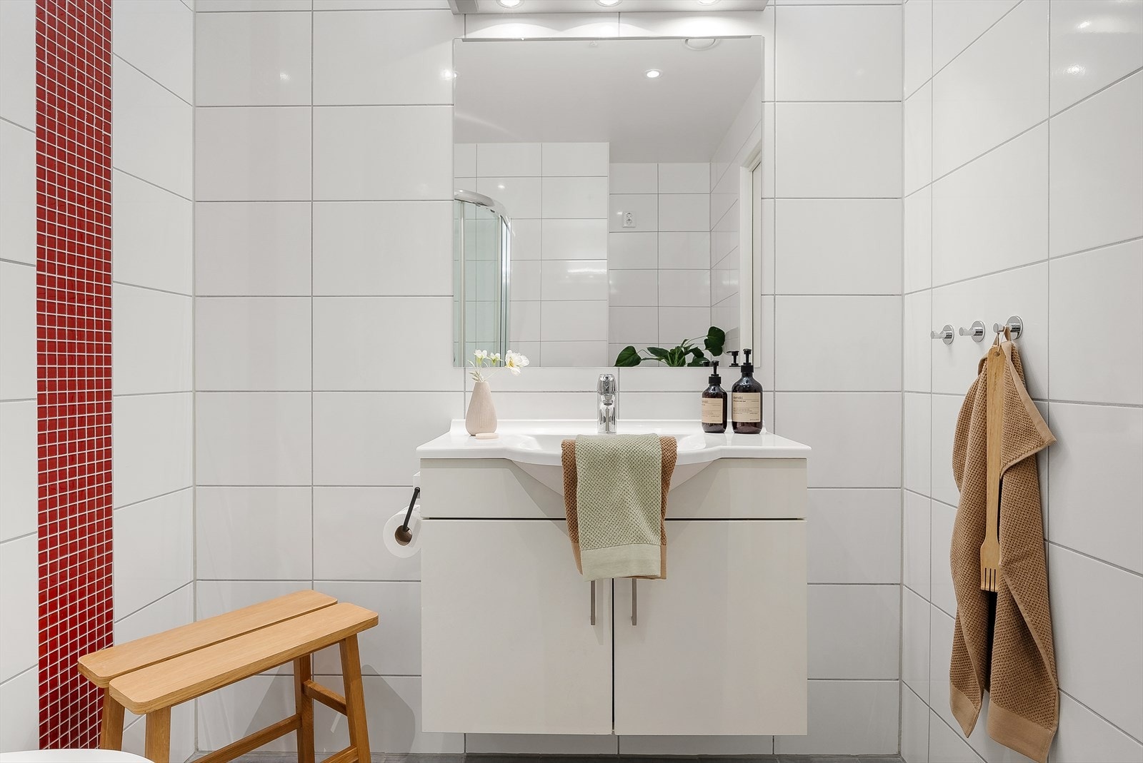 Servantsonen har en ren og moderne utforming med stor speilflate og underskap for oppbevaring. Den røde mosaikkdetaljen gir badet et friskt og særpreget uttrykk. Galleribilde