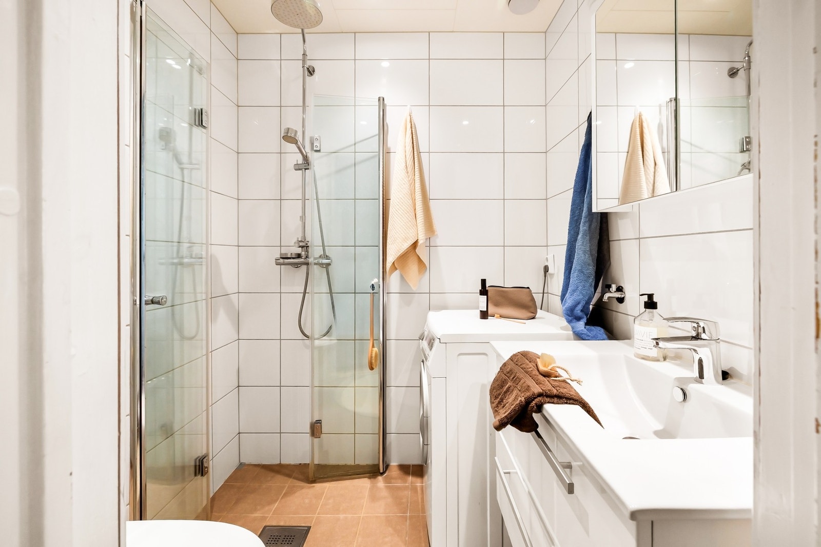 Badet er innredet med servant, dusj, vegghengt toalett, skap med speil og opplegg for vaskemaskin Galleribilde