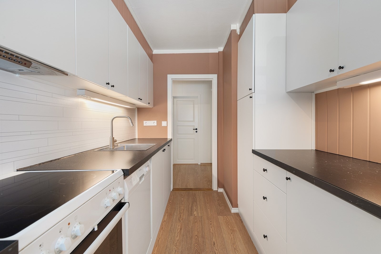 Ikea kjøkken med benkeplate av laminat. Kvitevarer som ventilator, kjøleskap og komfyr medfølger handelen. Galleribilde