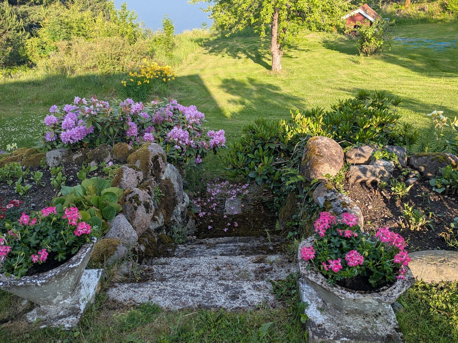 Eiendommen er velholdt med langvarig og gjennomført opparbeidelse, der beplantning, steinbed, trapper og gressarealer skaper et vakkert og strukturert hagemiljø (selgers bilde) Galleribilde