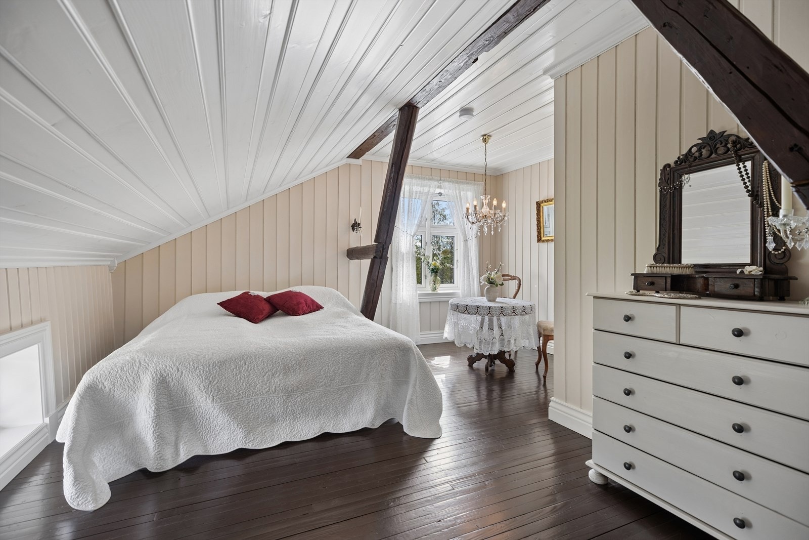 Romslig soverom med plass til stor seng, rundt bord og tilhørende stoler i klassisk stil. Et lunt og stemningsfullt rom med herskapelig preg. Galleribilde