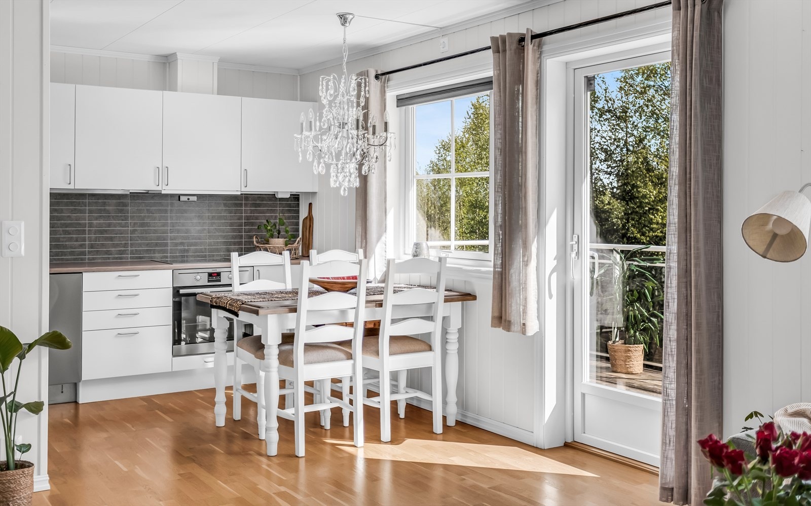 Kjøkkeninnredning med hvite, glatte fronter og laminert benkeplate med dobbel stålkum. Galleribilde
