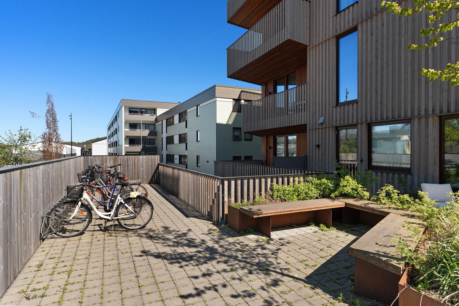 - Nyere leilighetsbygg med trekontruksjon | Steinbelagt gårdsplass med felles utvendig sykkelparkering - Galleribilde
