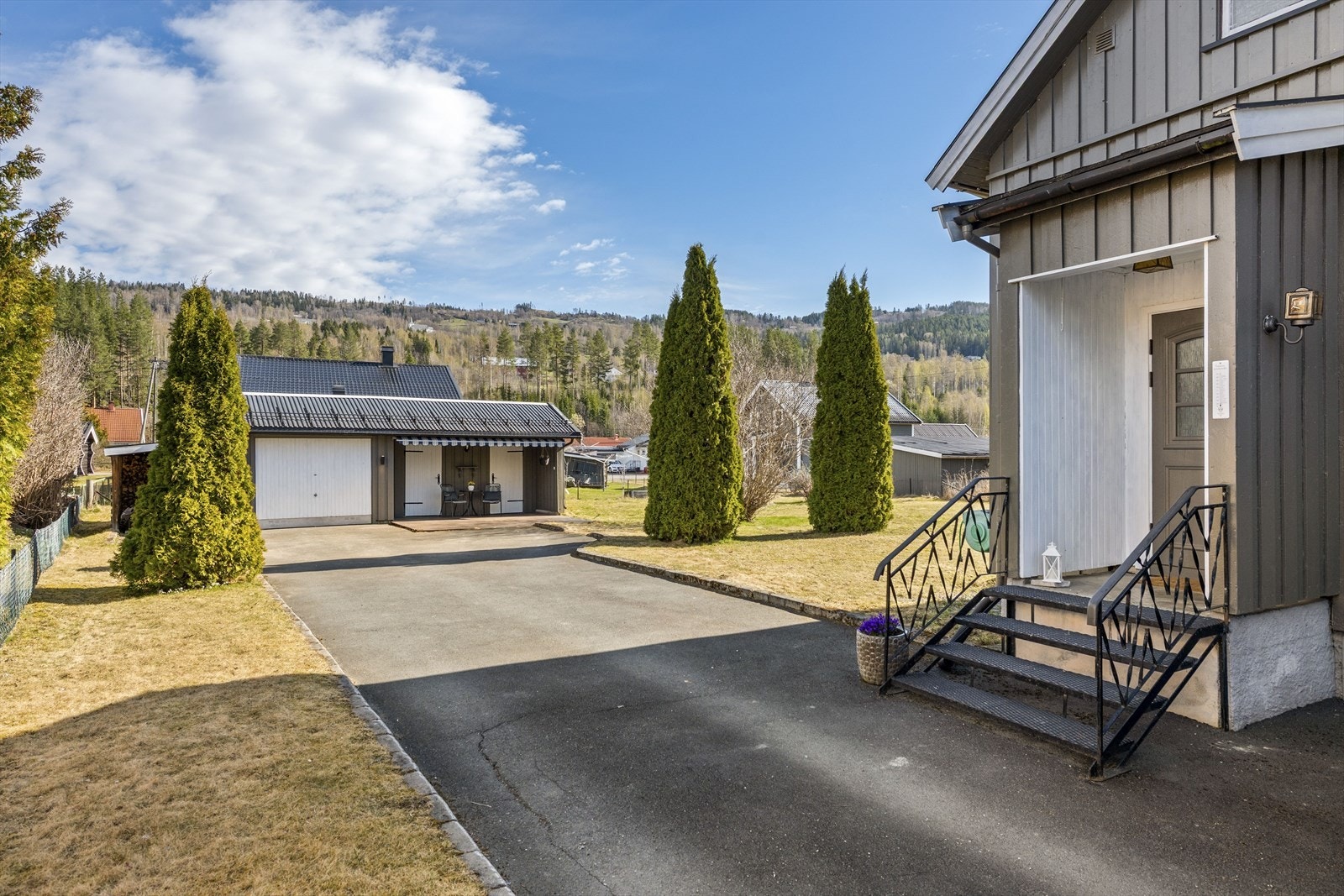 En renslig asfaltert gårdsplass og innkjøring med enkel adkomst til garasje og uthus. Galleribilde