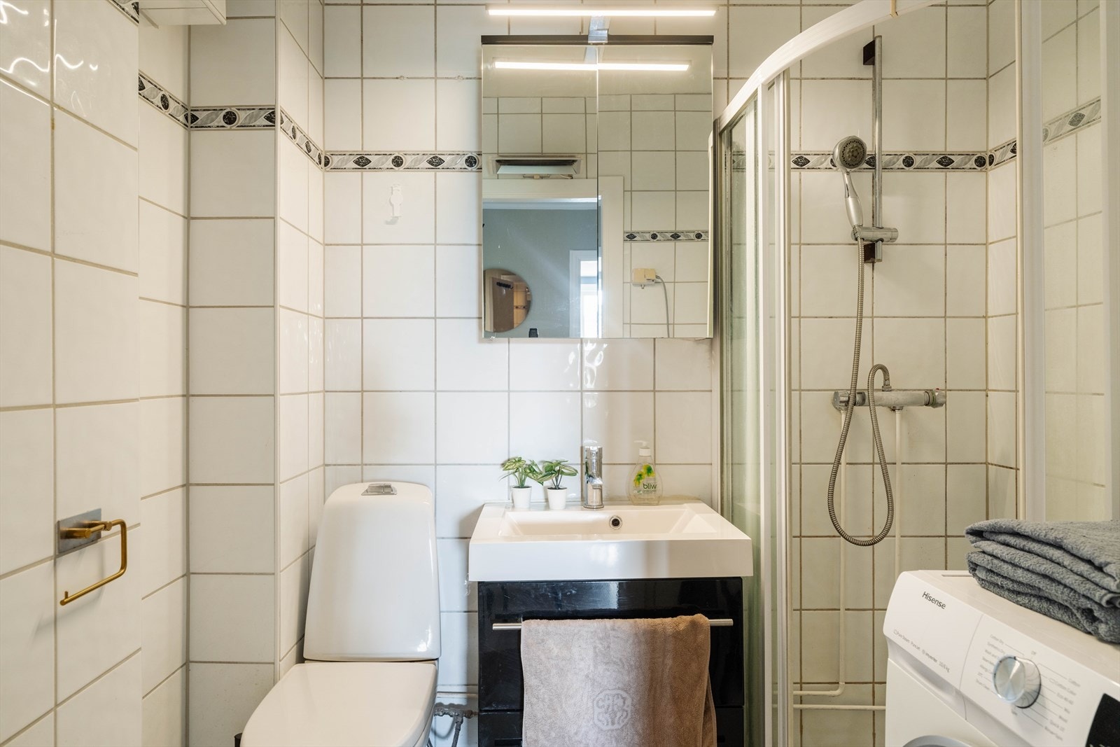 Badet er utstyrt med dusjhjørne, servantskap og gulvmontert toalett. Galleribilde