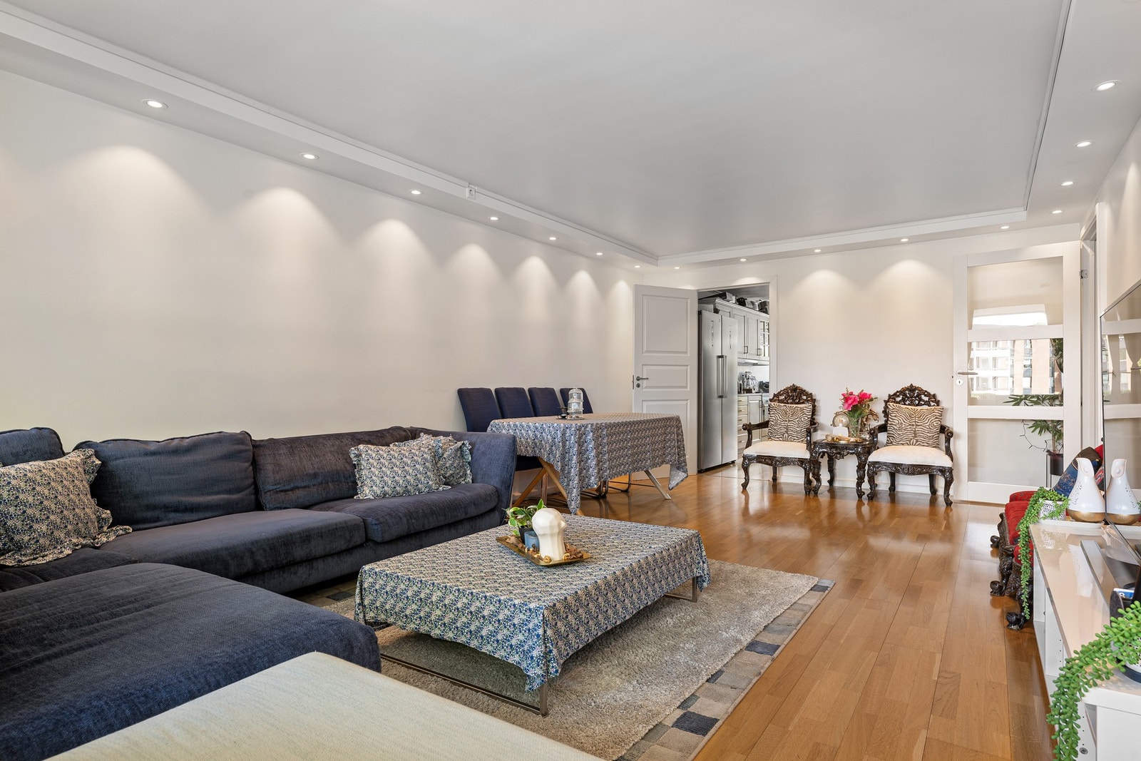 Downlights i taket gir stuen et varmt og behagelig lys, og parkettgulvet bidrar til et gjennomført og lyst helhetsinntrykk. Galleribilde