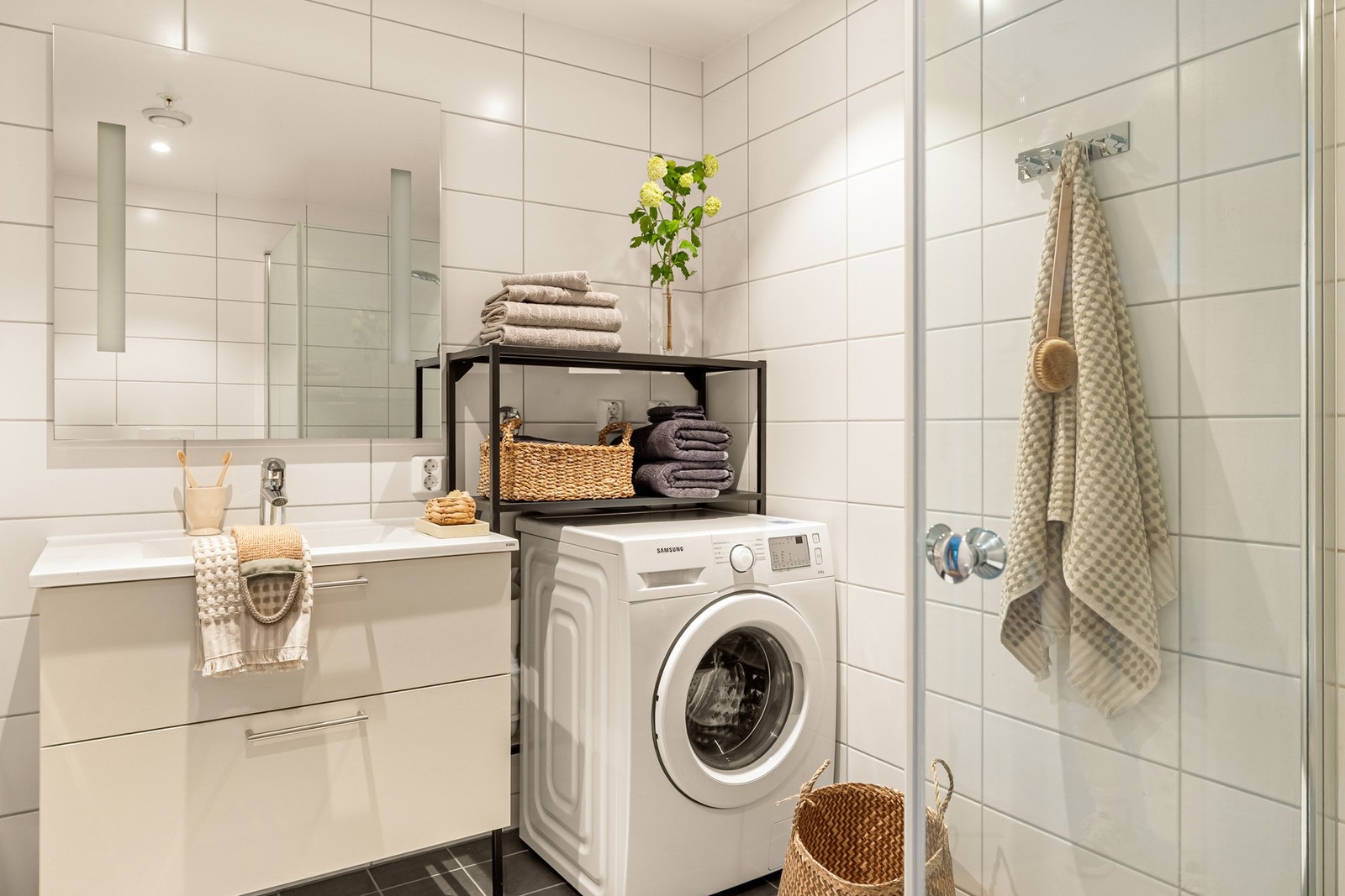 Badet er delikat innredet med vegghengt toalett, dusj med innfellbare dusjdører, servantmøbel med skuffer og speil med integrert belysning. Galleribilde