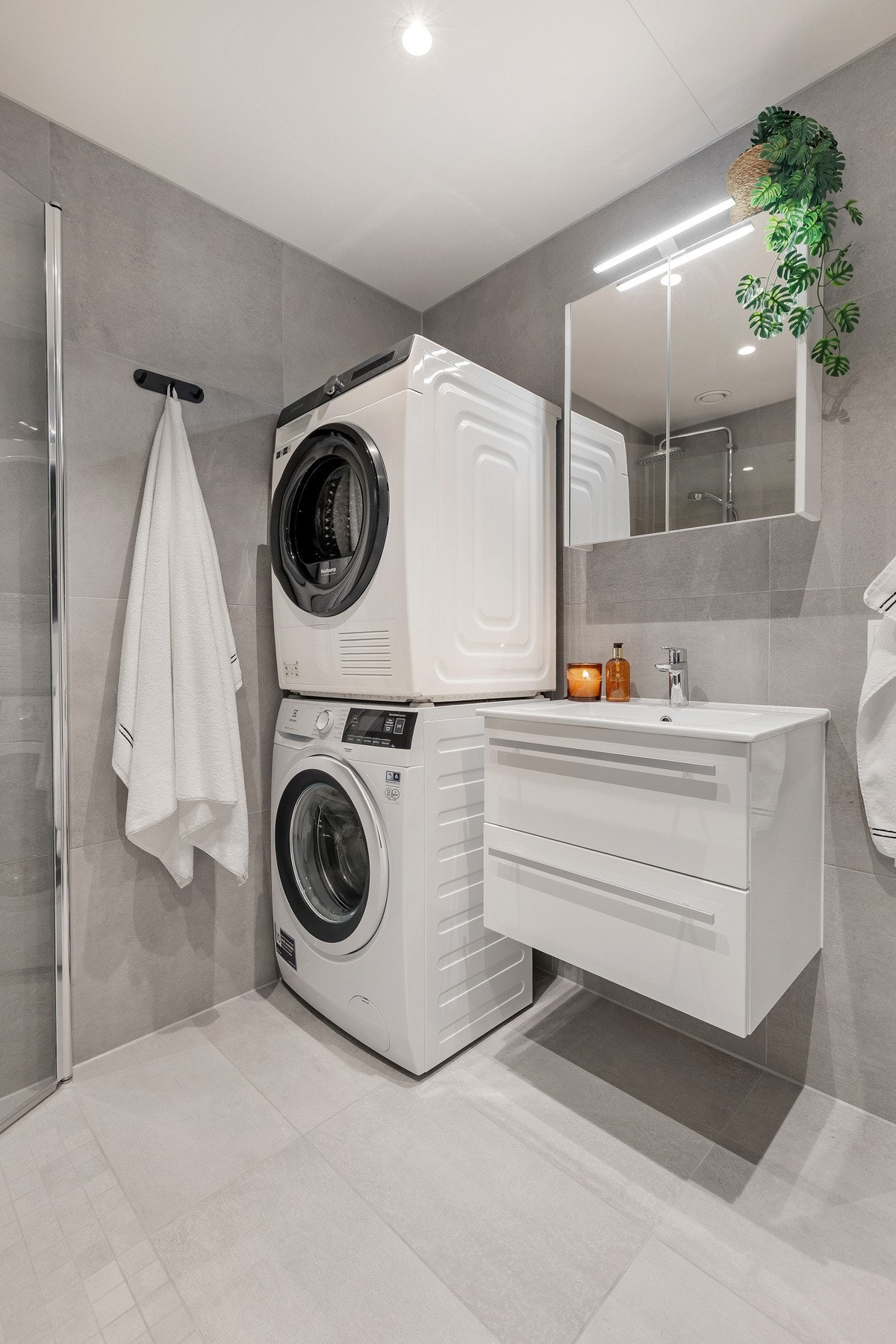 Badet er innredet med servantinnredning, vegghengt toalett, dusjløsning og opplegg for vaskemaskin og tørketrommel. Galleribilde